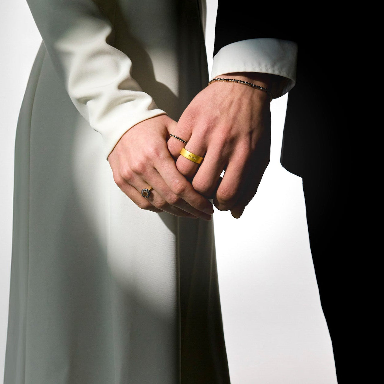 two lovers holding hands on their wedding day, wearing mesmerising gold rings