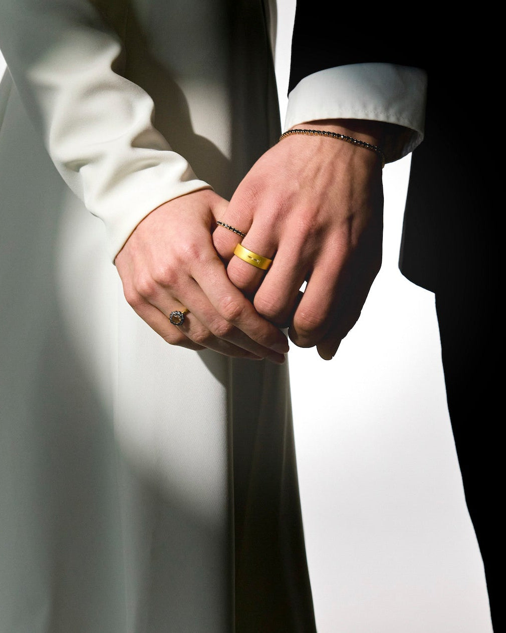 two lovers holding hands on their wedding day, wearing mesmerising gold rings