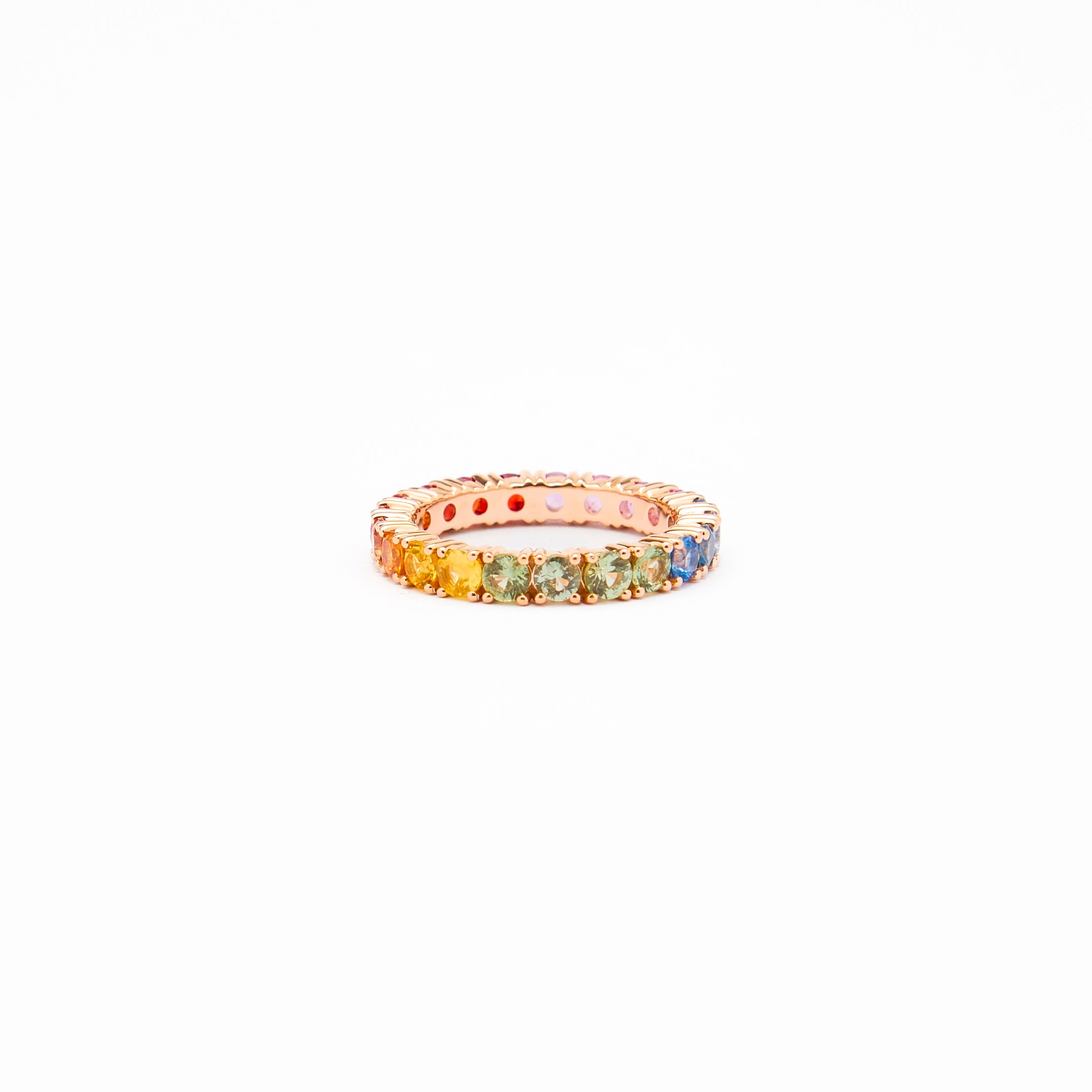 Beautiful eternity rainbow sapphires ring in rose gold on white background.