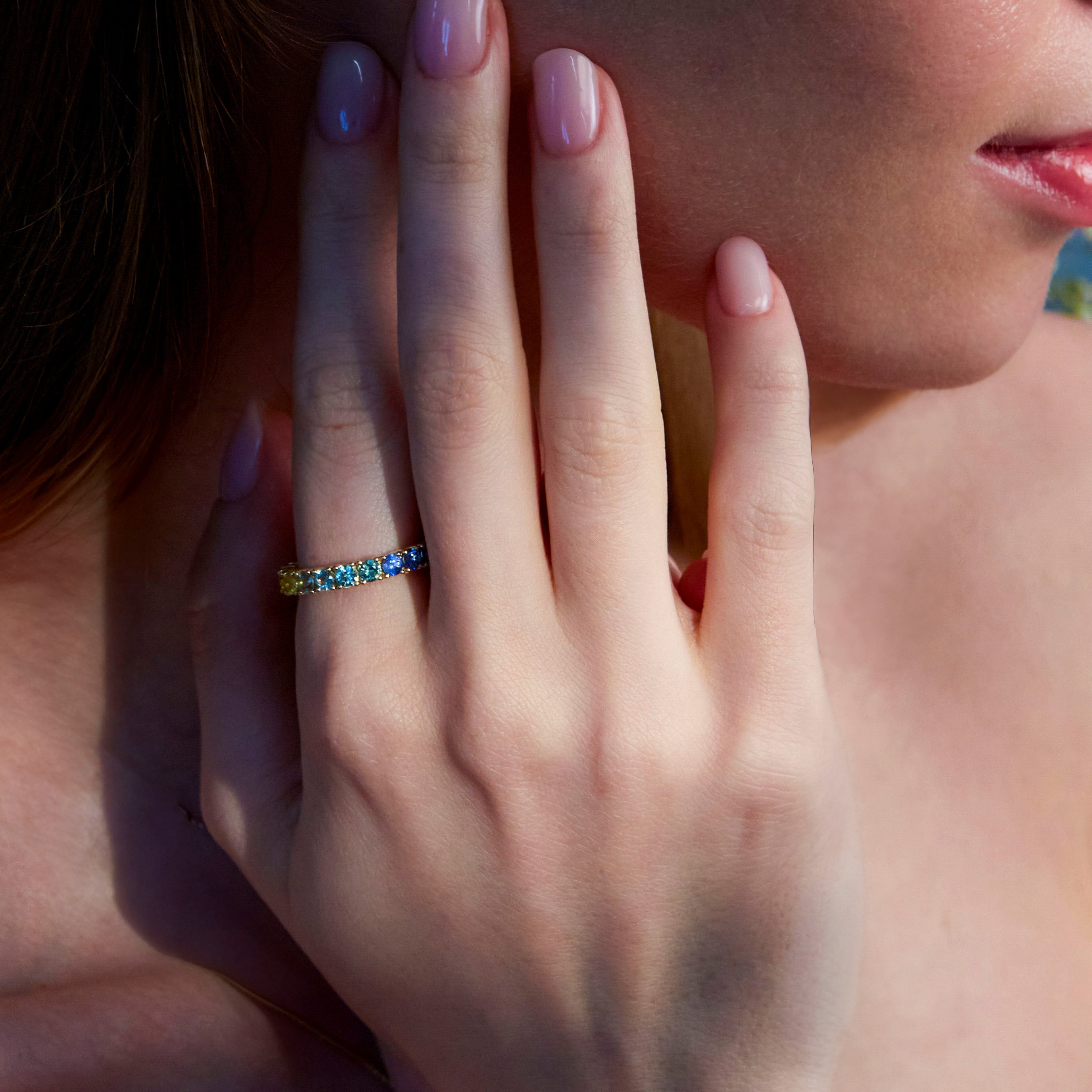 Beautiful eternity rainbow sapphires ring on hand.