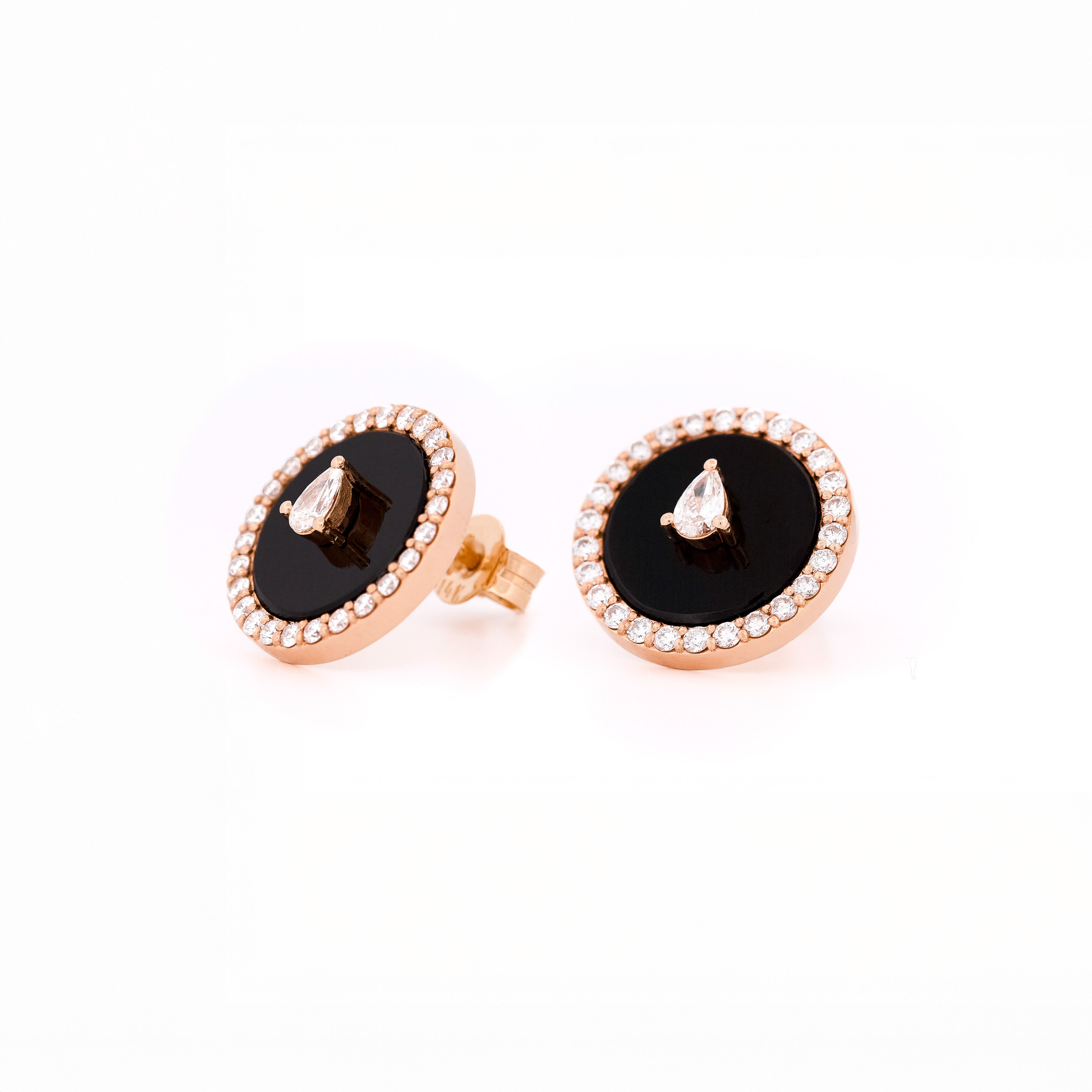 Pair of earrings with black onyx center stone and teardrop and round shape diamonds accents on a white background