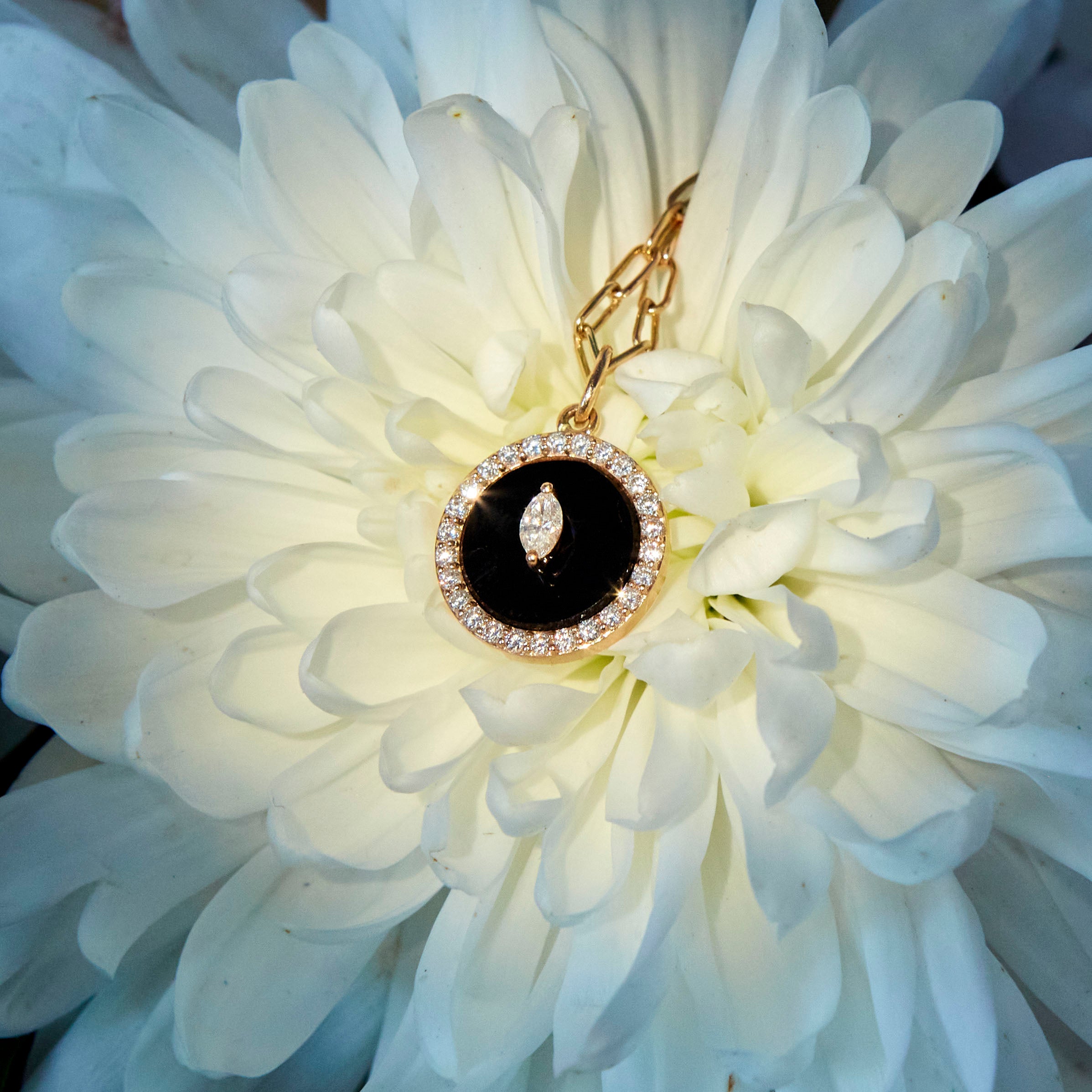 Black Onyx and White diamonds protection pendant on a flower. Pandant Protection cu Onix negru si diamante asezat pe o floare, dahlia.
