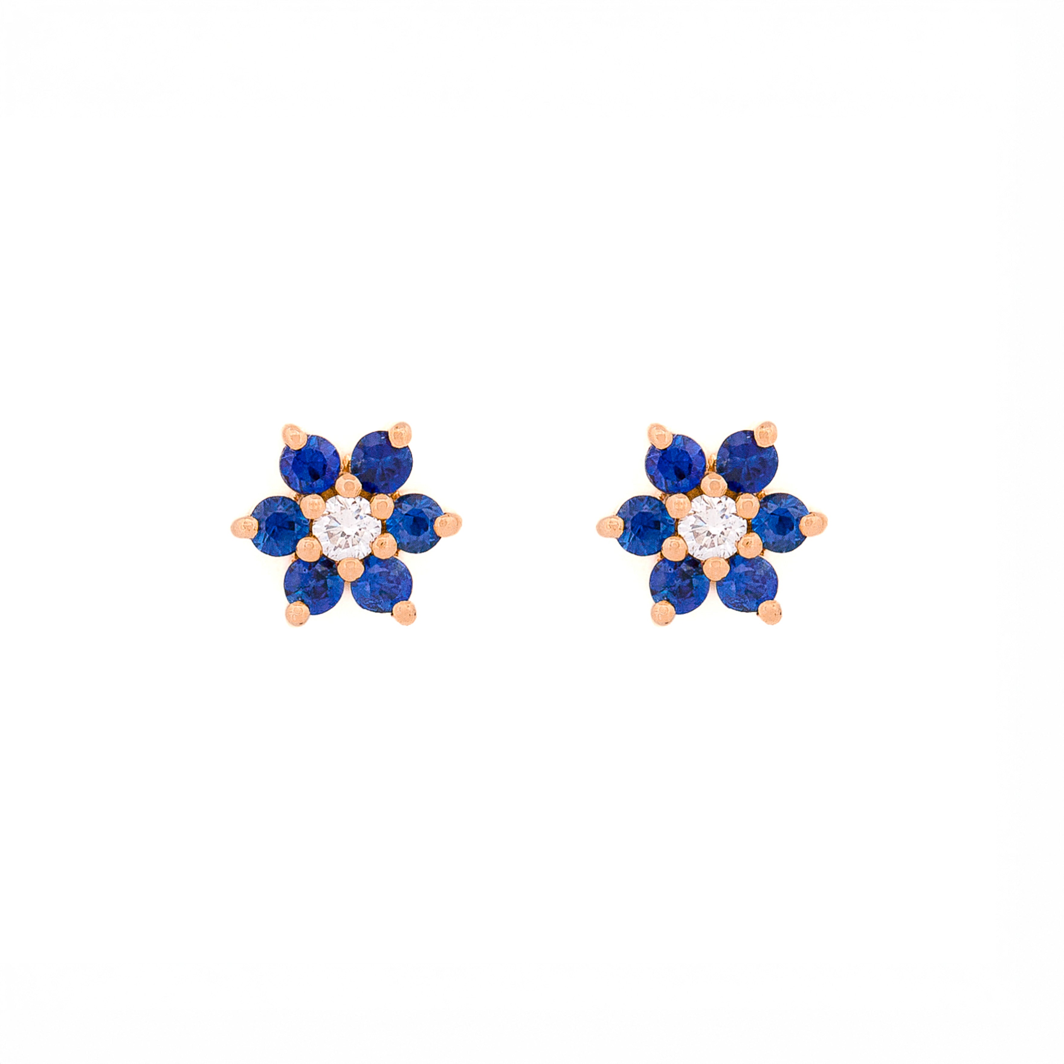Pair of floral earrings with blue sapphires and diamonds and gold accents on a white background