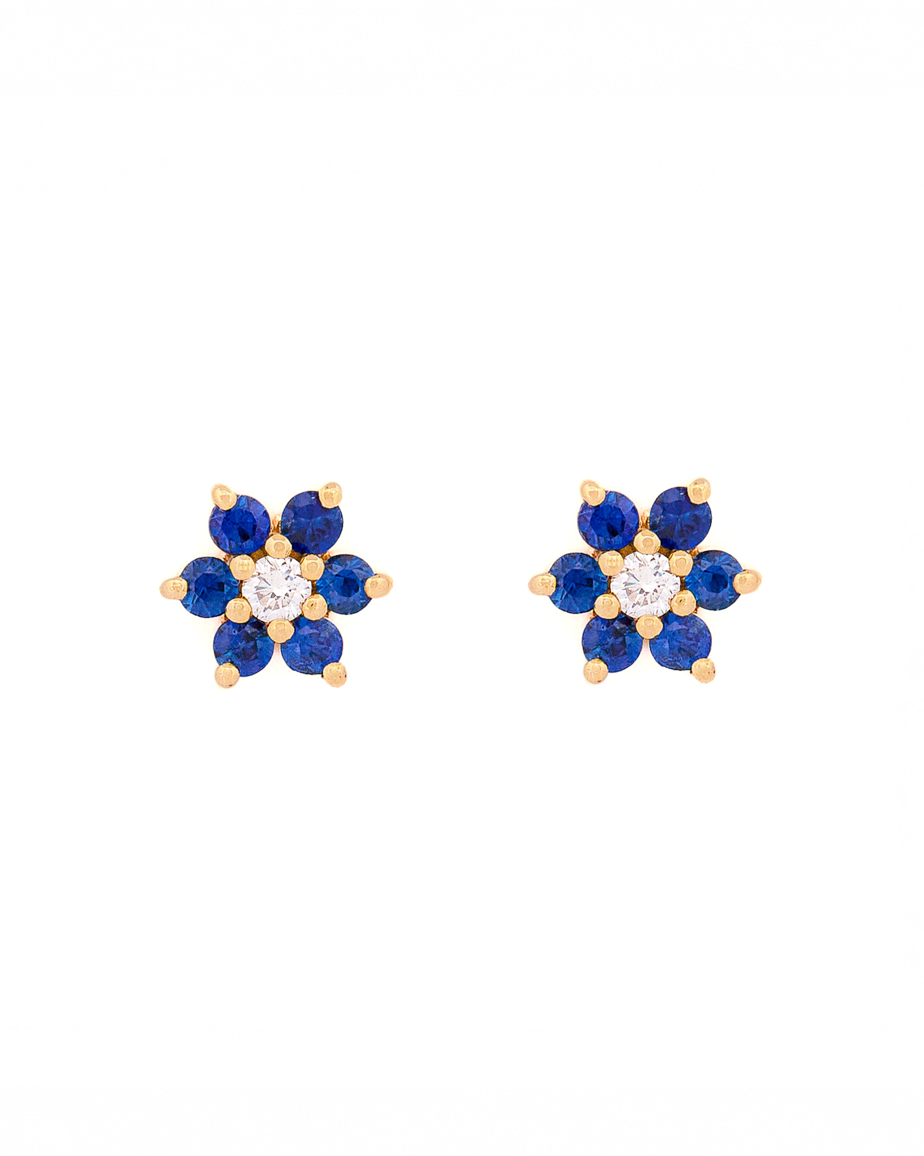 Pair of floral earrings with blue sapphires and diamonds and yellow gold accents on a white background
