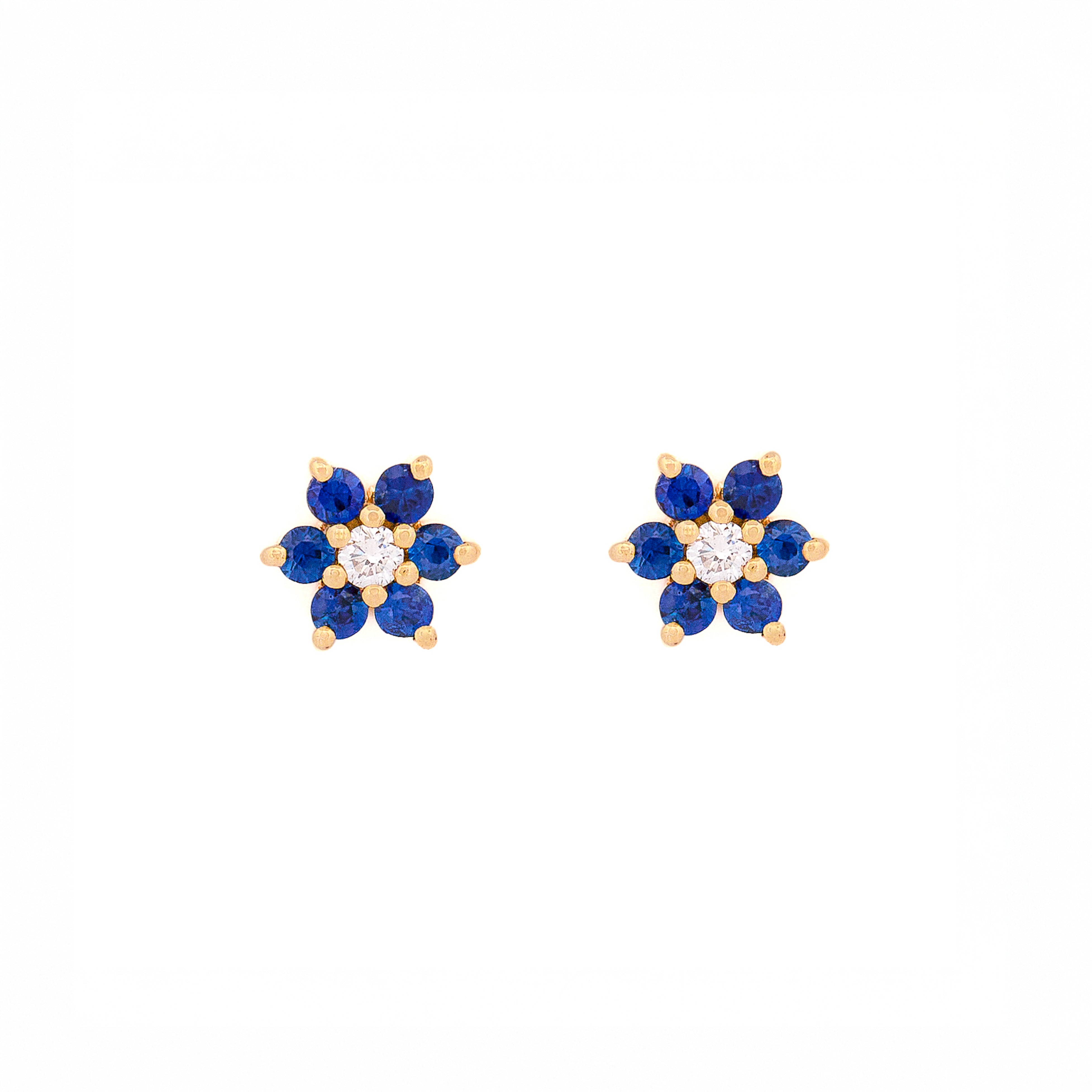 Pair of floral earrings with blue sapphires and diamonds and yellow gold accents on a white background