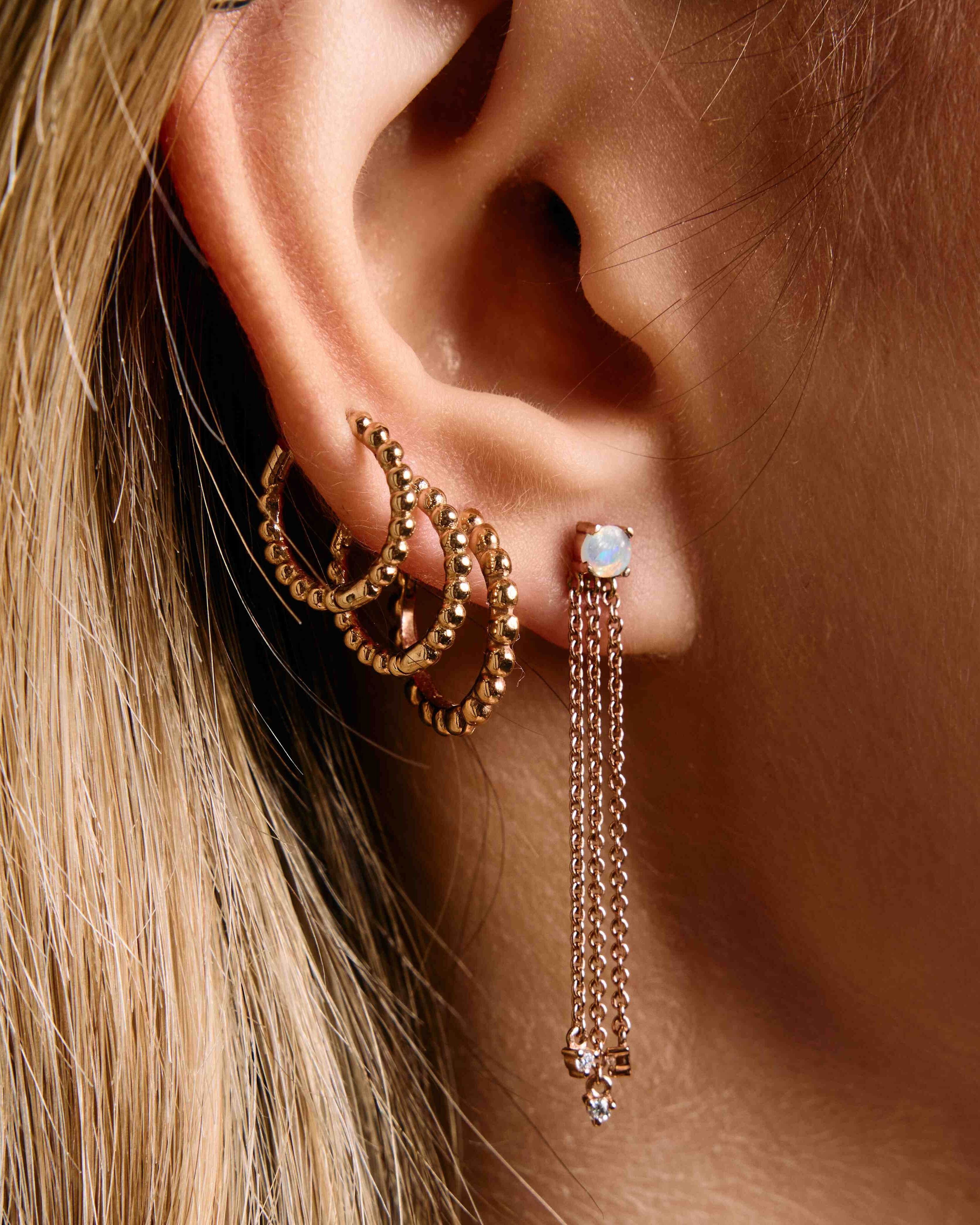 A pair of gold hoop earrings with a beaded design, mix and match on ear