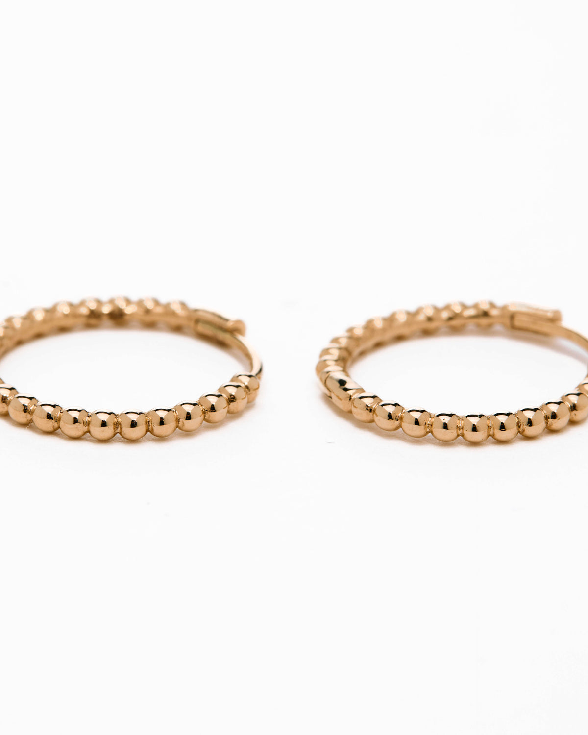 A pair of yellow gold hoop earrings with a bubbly design, displayed against a white background.