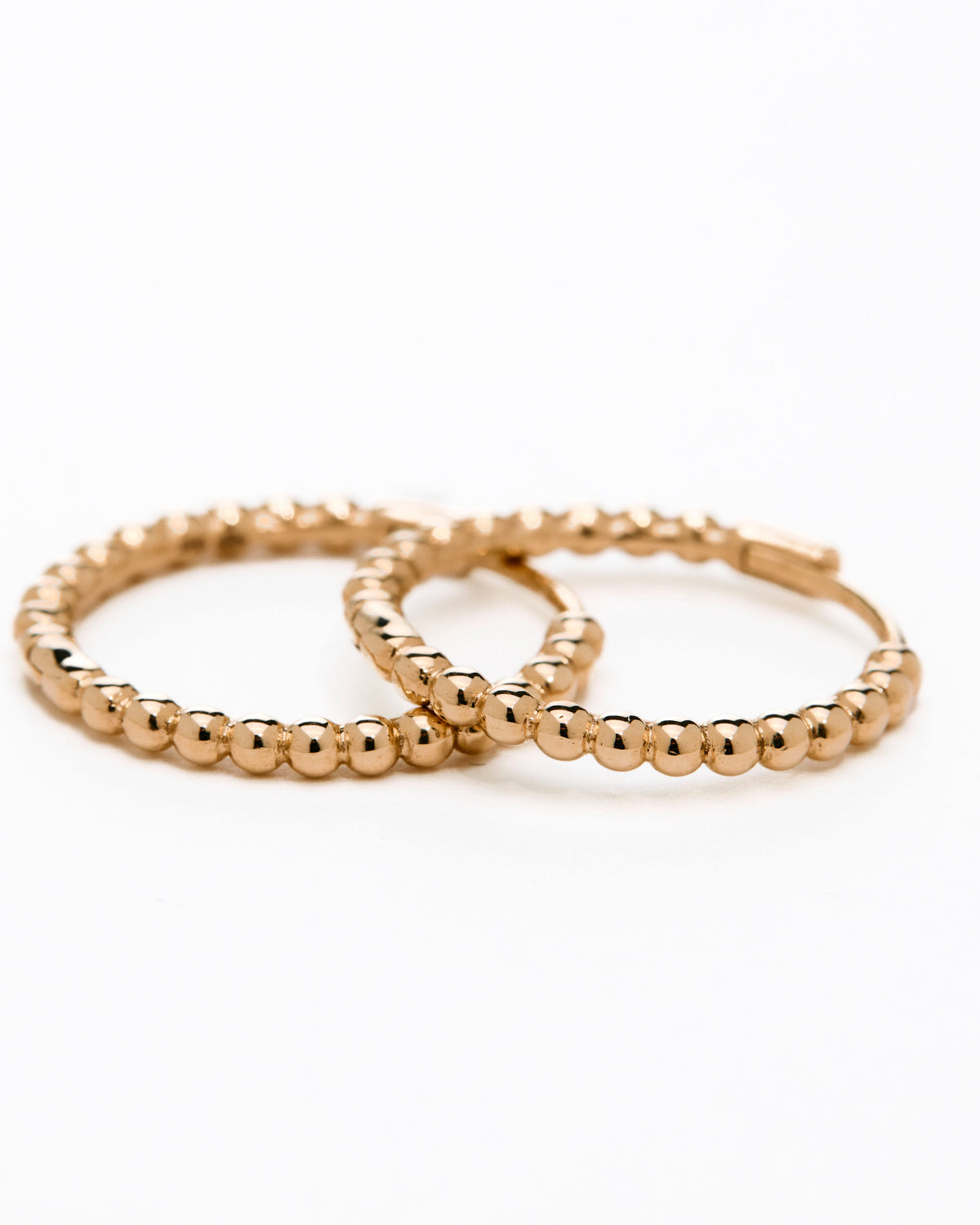 A pair of yellow gold hoop earrings with a bubbly design, displayed against a white background.