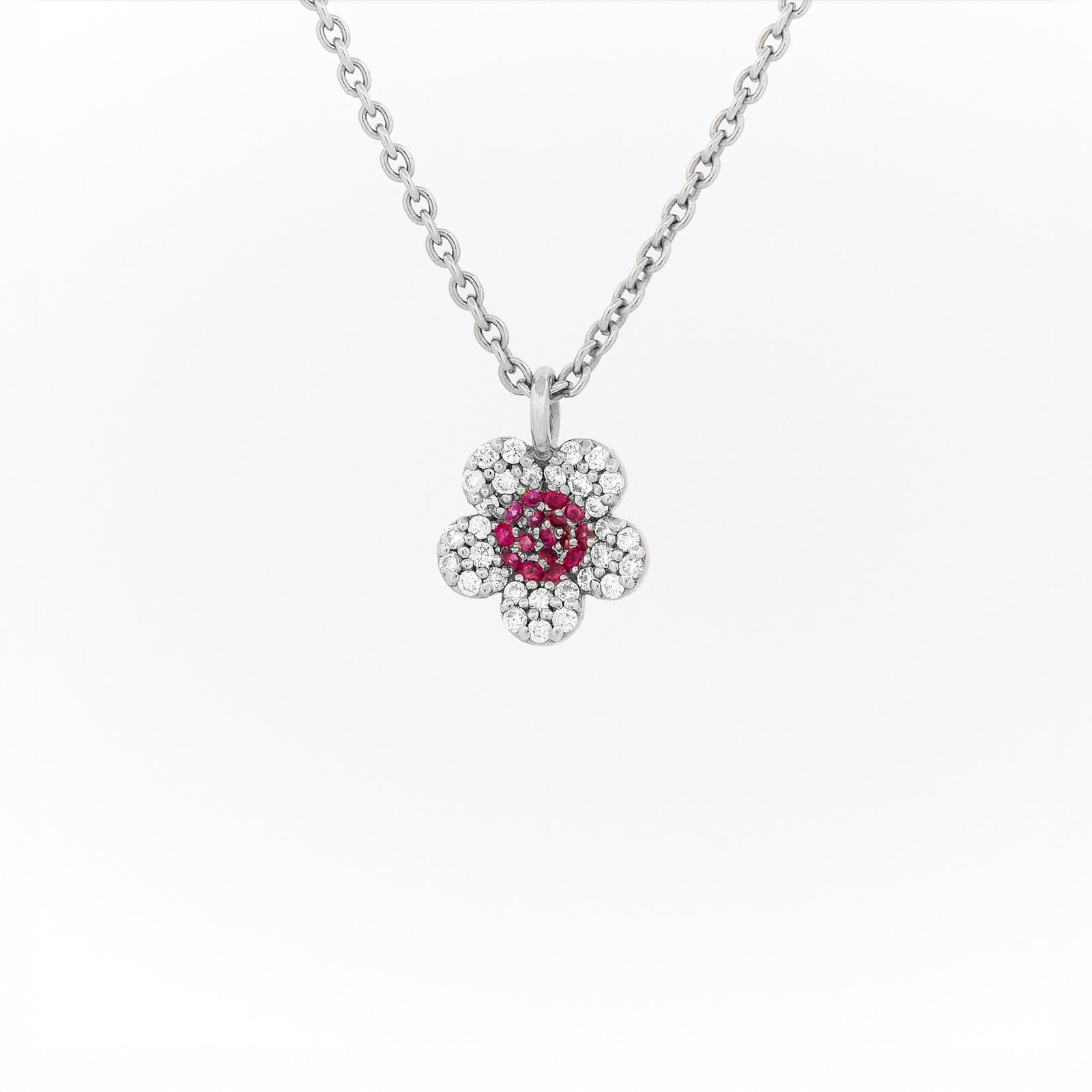 White gold necklace with a flower-shaped pendant featuring rubies and diamonds on a white background