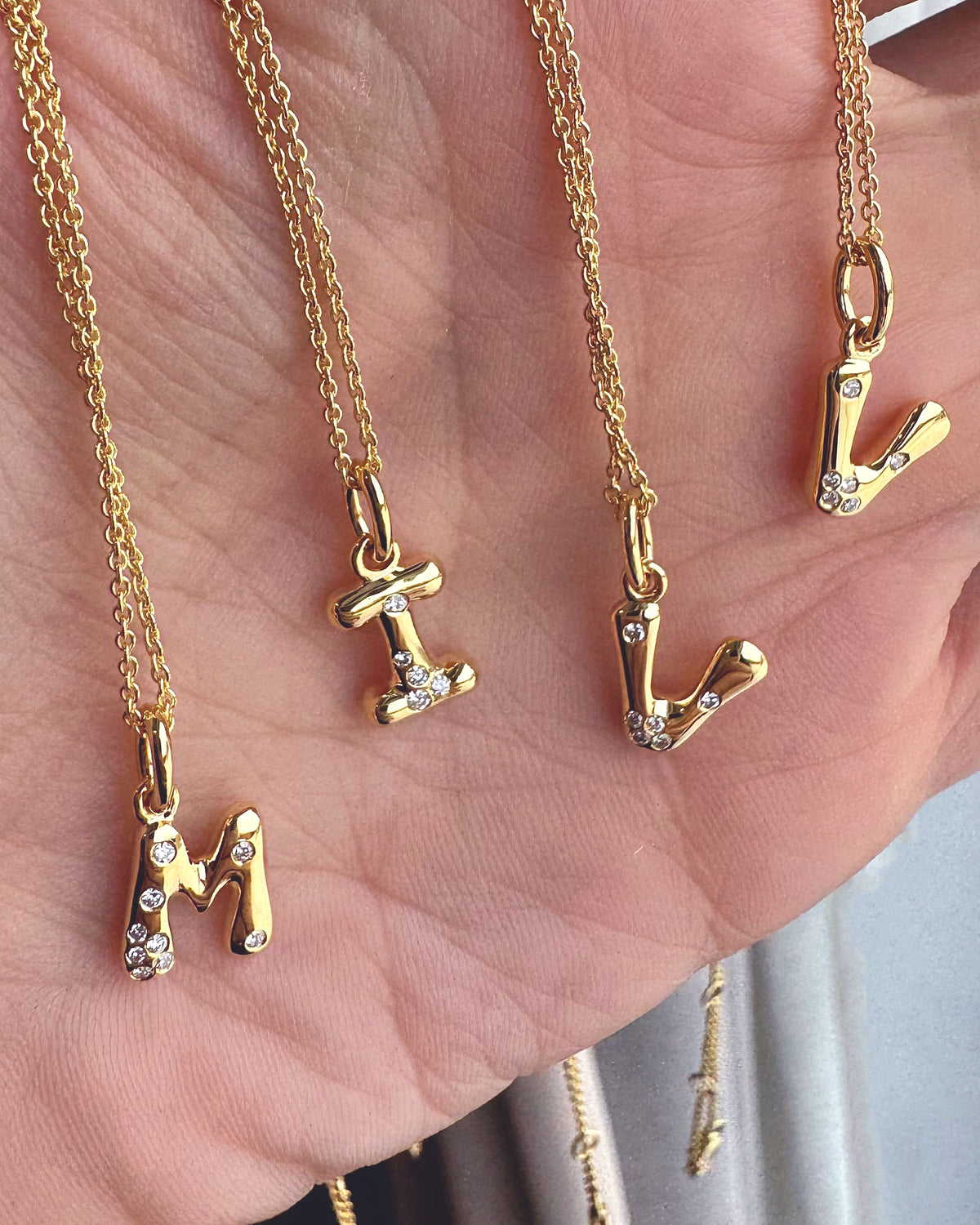 Gold necklaces with letter pendants on a hand