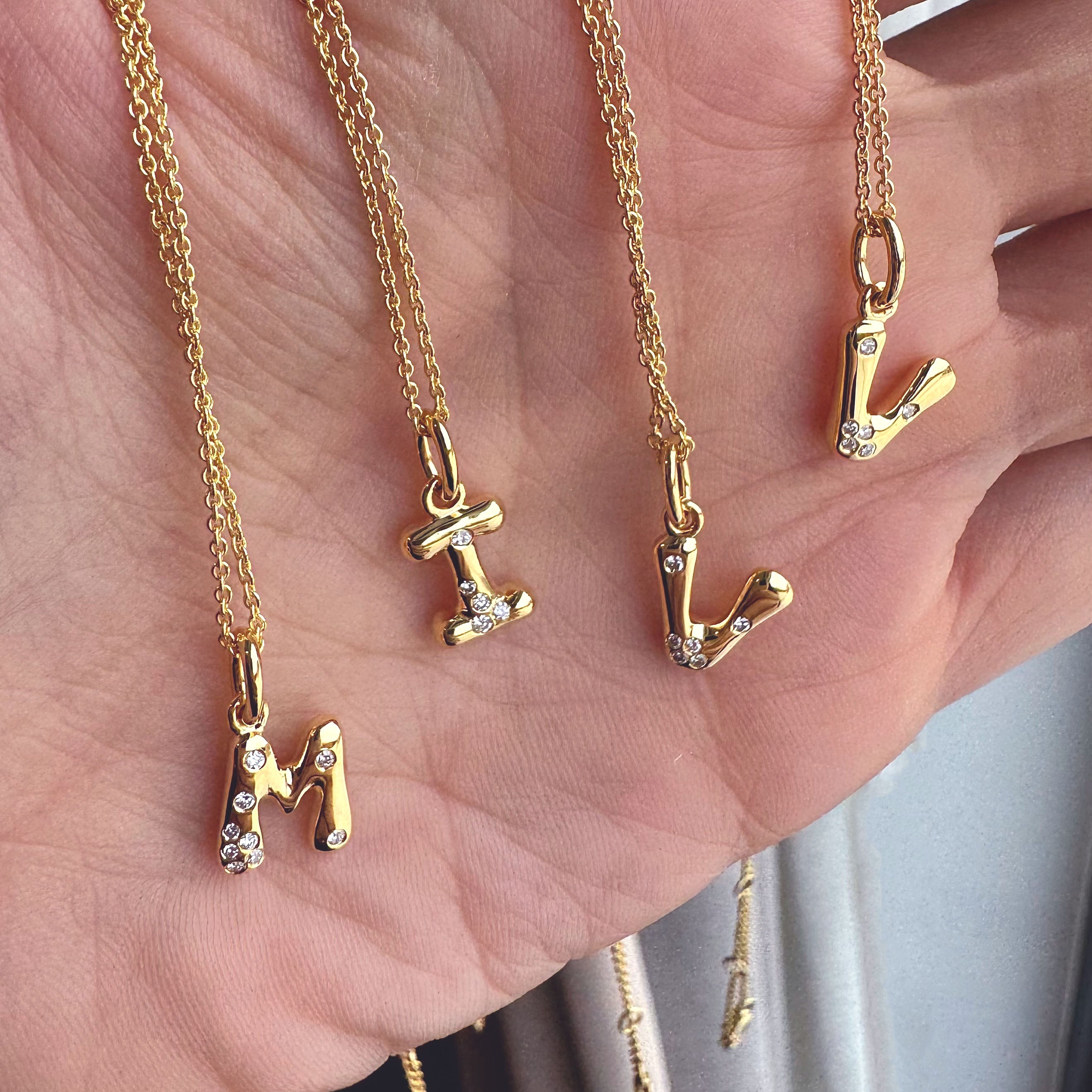 Gold necklaces with letter pendants on a hand