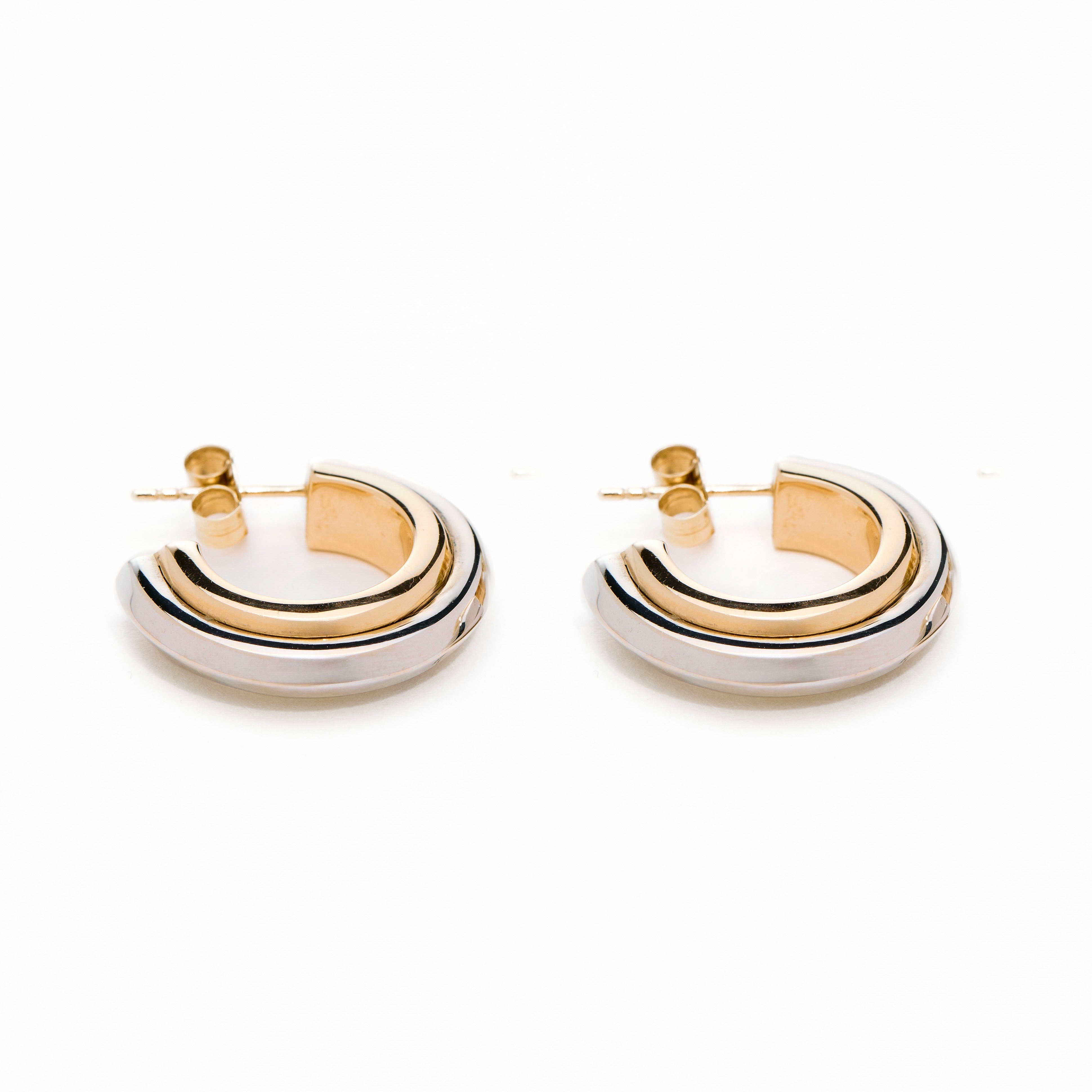Pair of thick hoop earrings with gold and white gold design on a white background