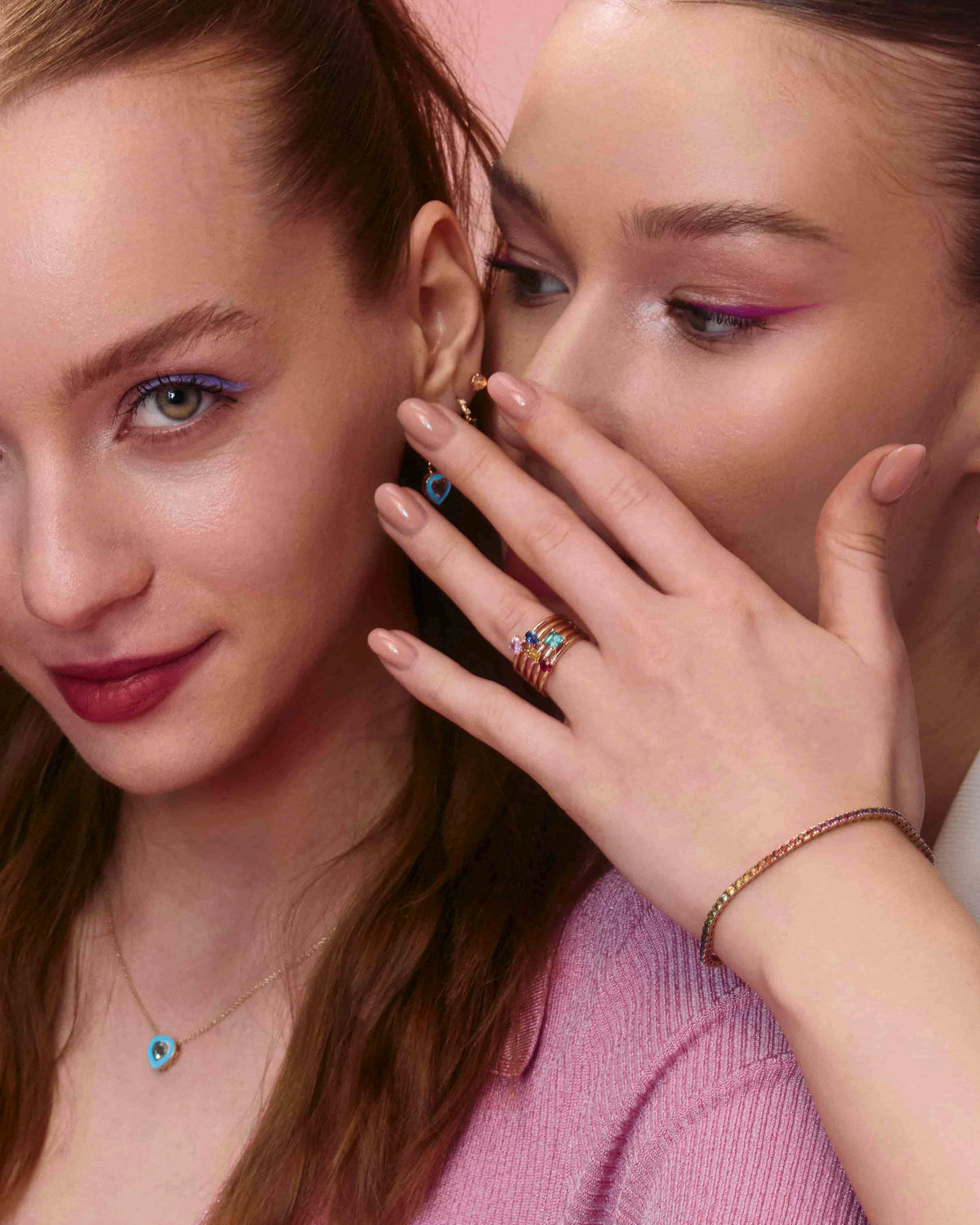A pair of yellow gold hoop earrings with a bubbly design, enamel heart earring accessories and mix and match rings, displayed on models.
