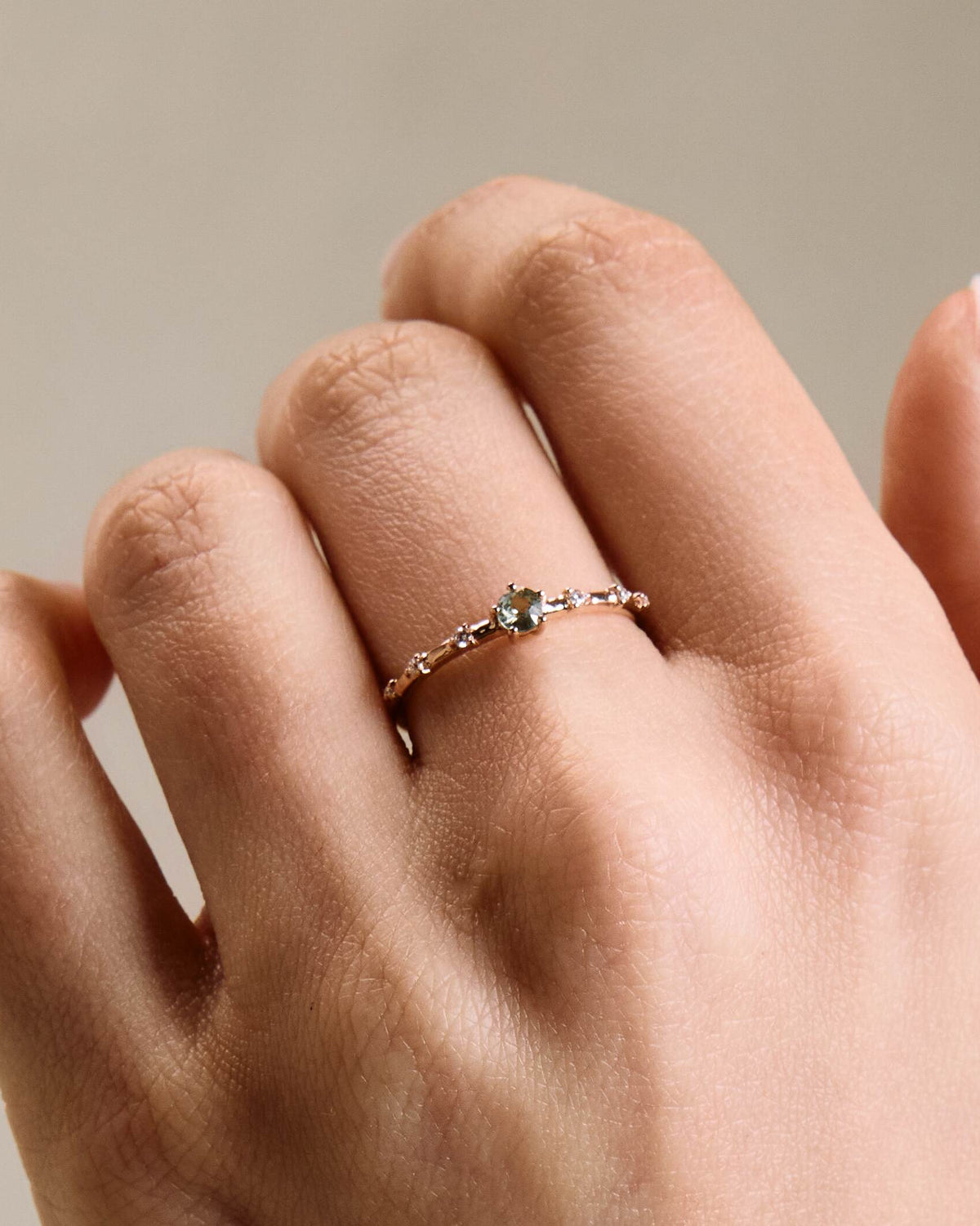A gold band ring featuring a central sapphire with smaller diamond accents around it, presented on a hand
