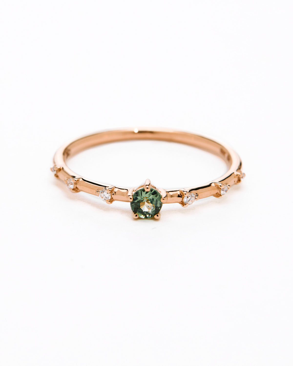 A gold band ring featuring a central sapphire with smaller diamond accents around it, presented against a white background.