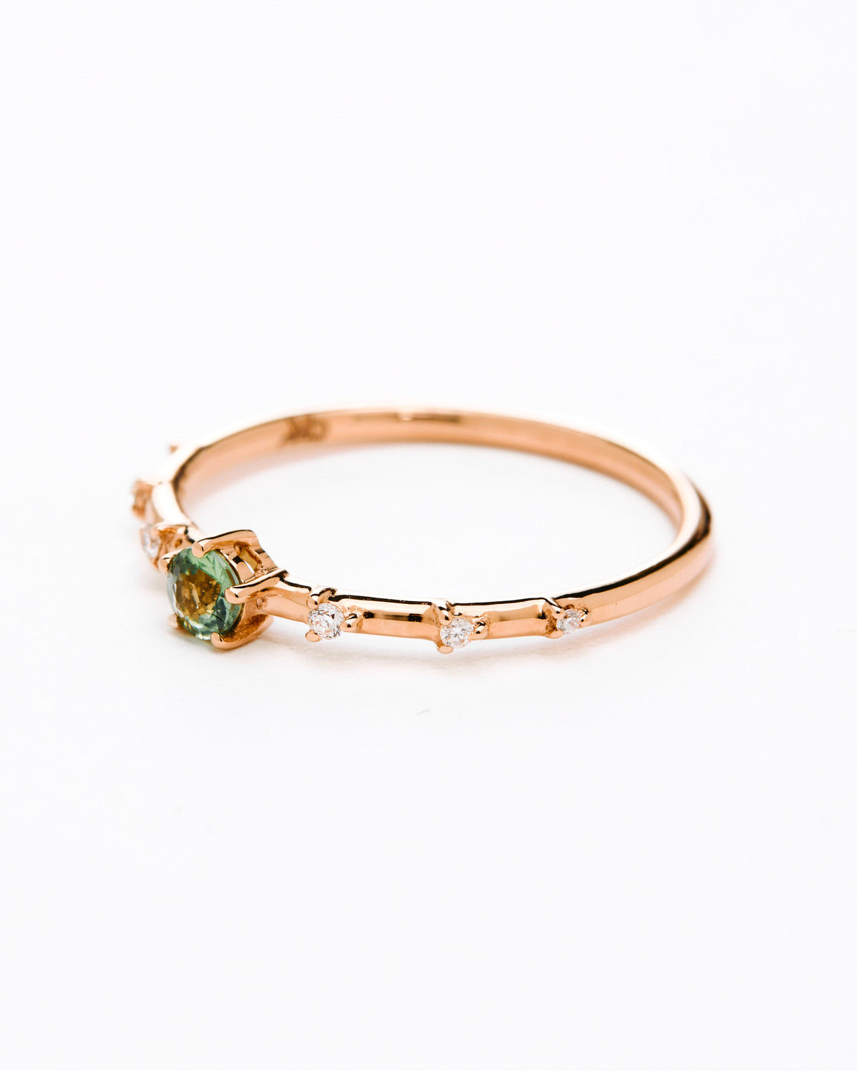 A gold band ring featuring a central sapphire with smaller diamond accents around it, presented against a white background.