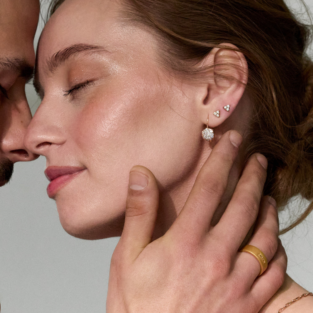 Close-up of a couple having an intimate moment, with a focus on gold and diamonds jewelry, including earrings and a wedding band ring.