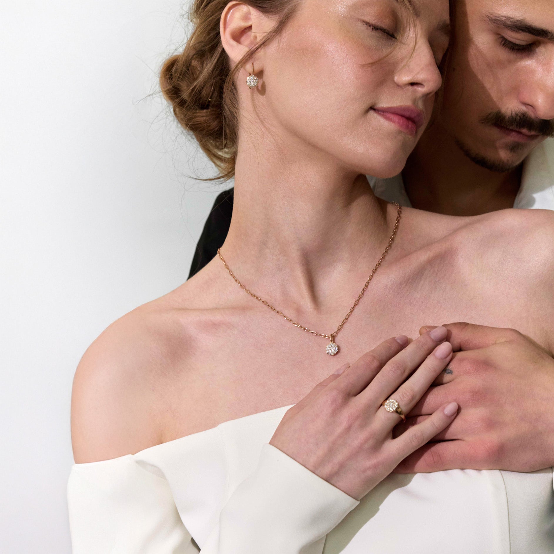 Couple wearing diamonds jewelry set with a plain background