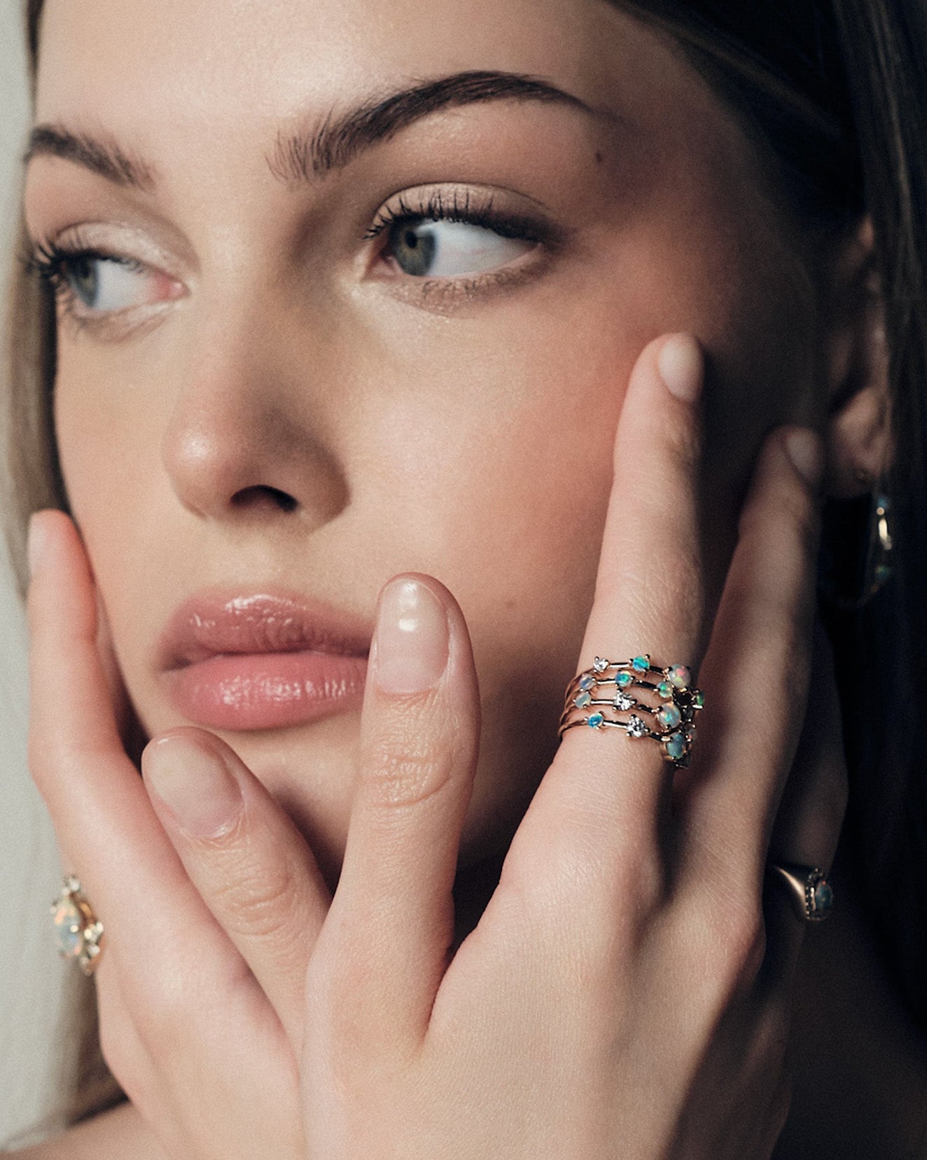 Woman wearing stackable Australian Opals and Diamonds Dew Drops Collection, with a visible Australian Opals, close-up of face and hand.