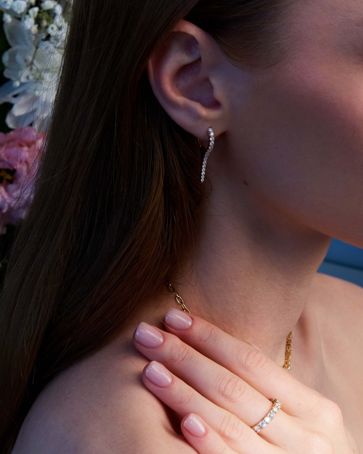 A pair of rose gold earrings with natural diamond drops, featuring a minimalist design on a ear.