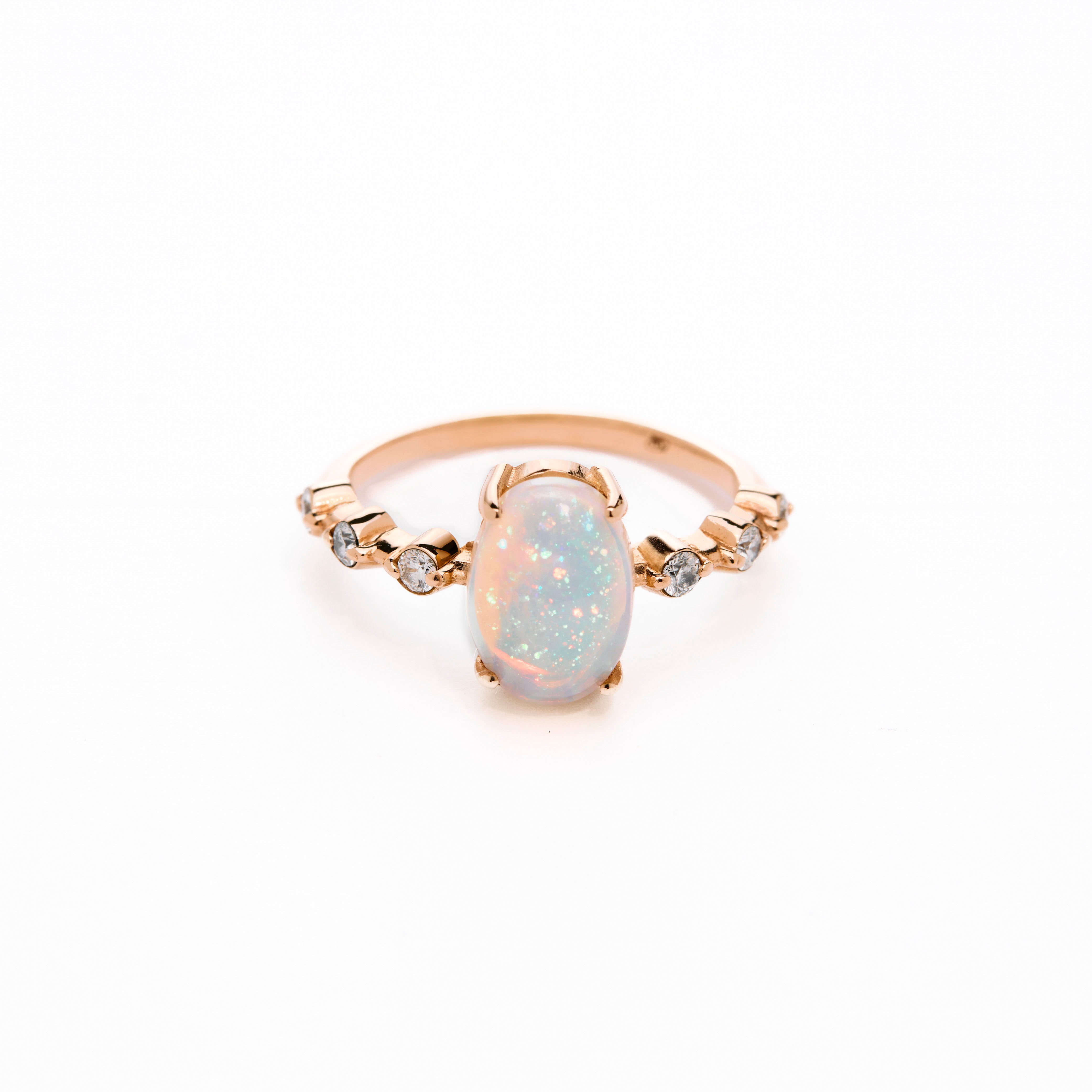 a gold ring with an opal center stone and white diamond accents on the band