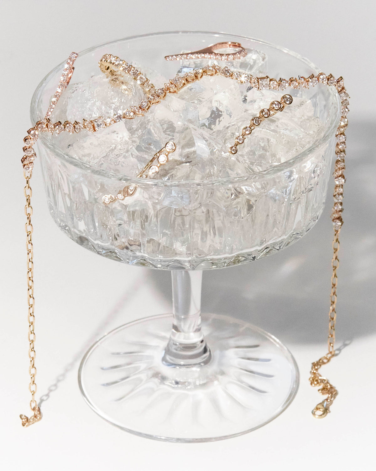 A cocktail glass with the perfect brew in it, diamond jewellery of all sorts on ice, earrings, choker and a eternity ring.