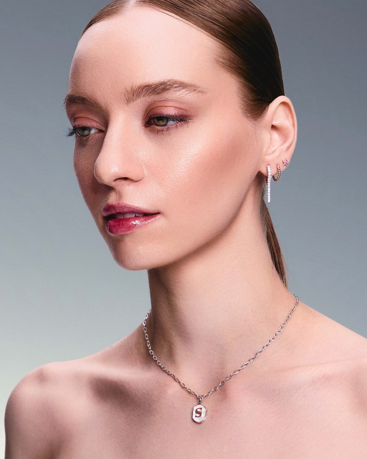 A pair of rose gold earrings with natural diamond drops, featuring a minimalist design on a girl.