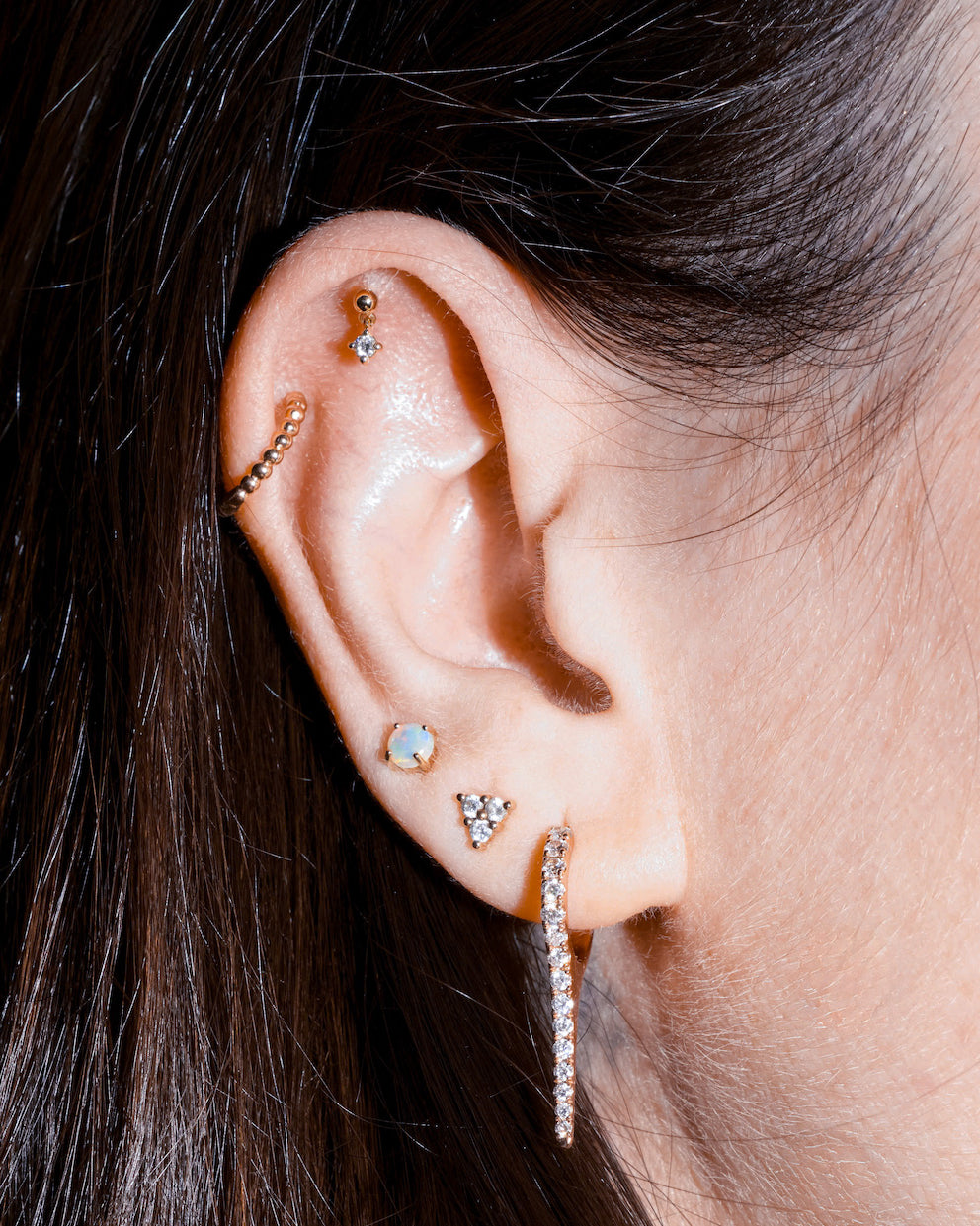 Close-up of an ear with multiple diamond earrings on a blurred background