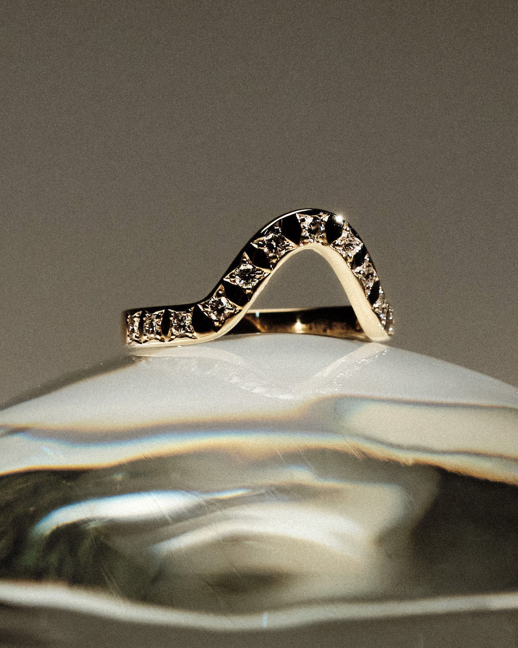 Yellow gold 2.5 mm band ring with 13 round diamonds diamonds on a gray background.