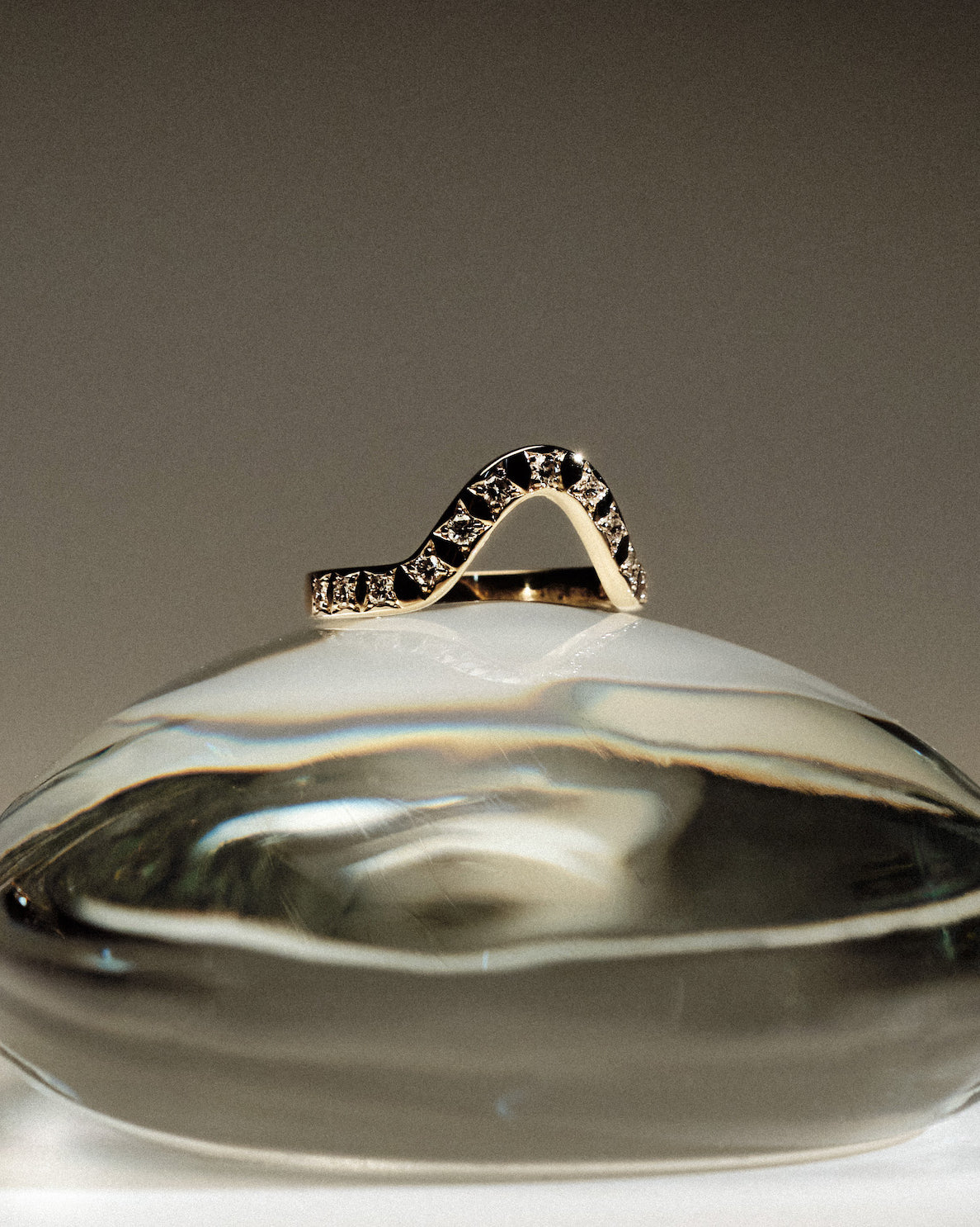 Yellow gold 2.5 mm band ring with 13 round diamonds diamonds on a glass ball against a gray background.