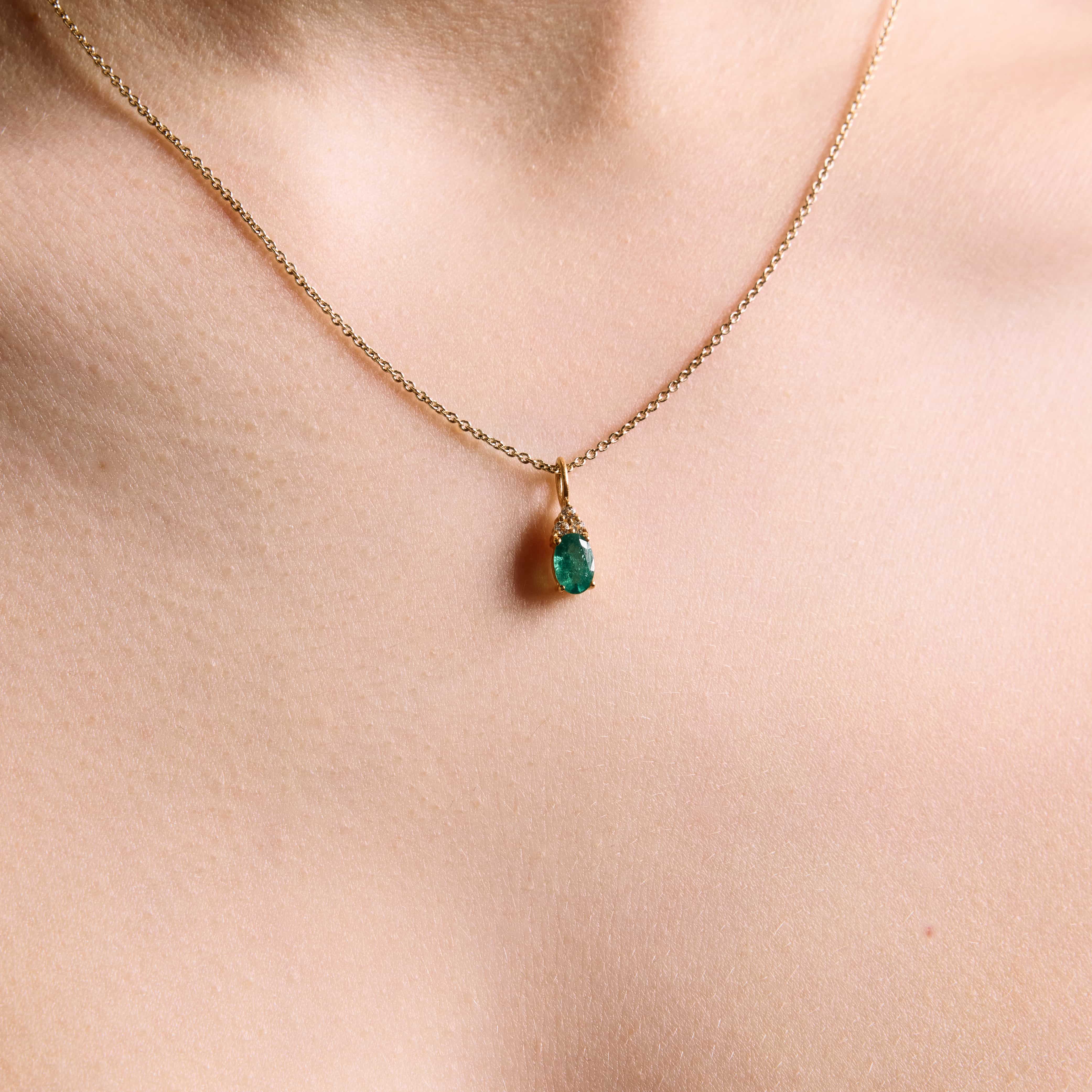 emerald pendant, emerald pendant with diamonds, emerald pendant on string chain, emerald pendant in yellow gold on model close up