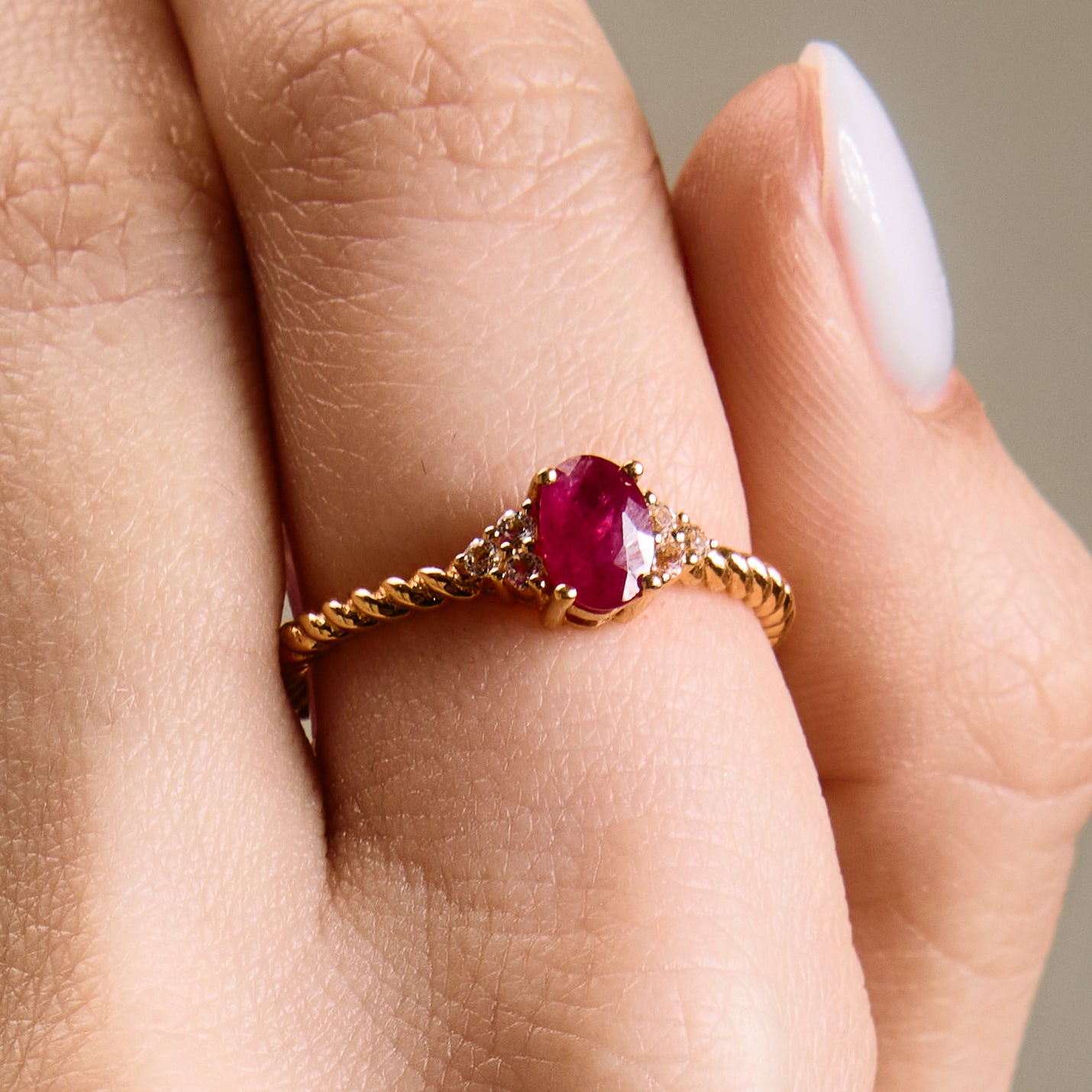 Romantic oval ruby ring with twisted band and cluster diamonds details