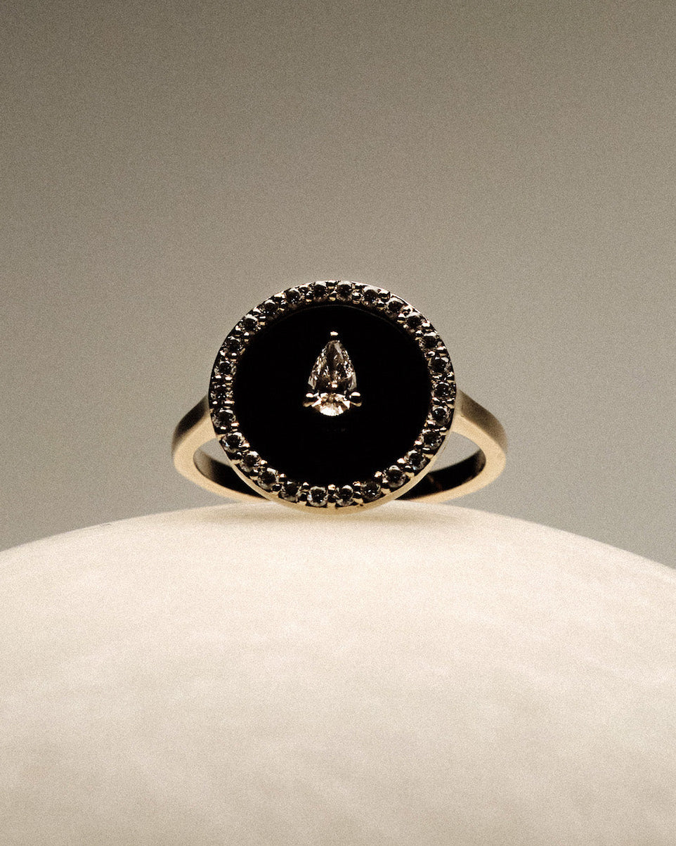 Black Onyx and diamonds Gold Ring on a round marble.