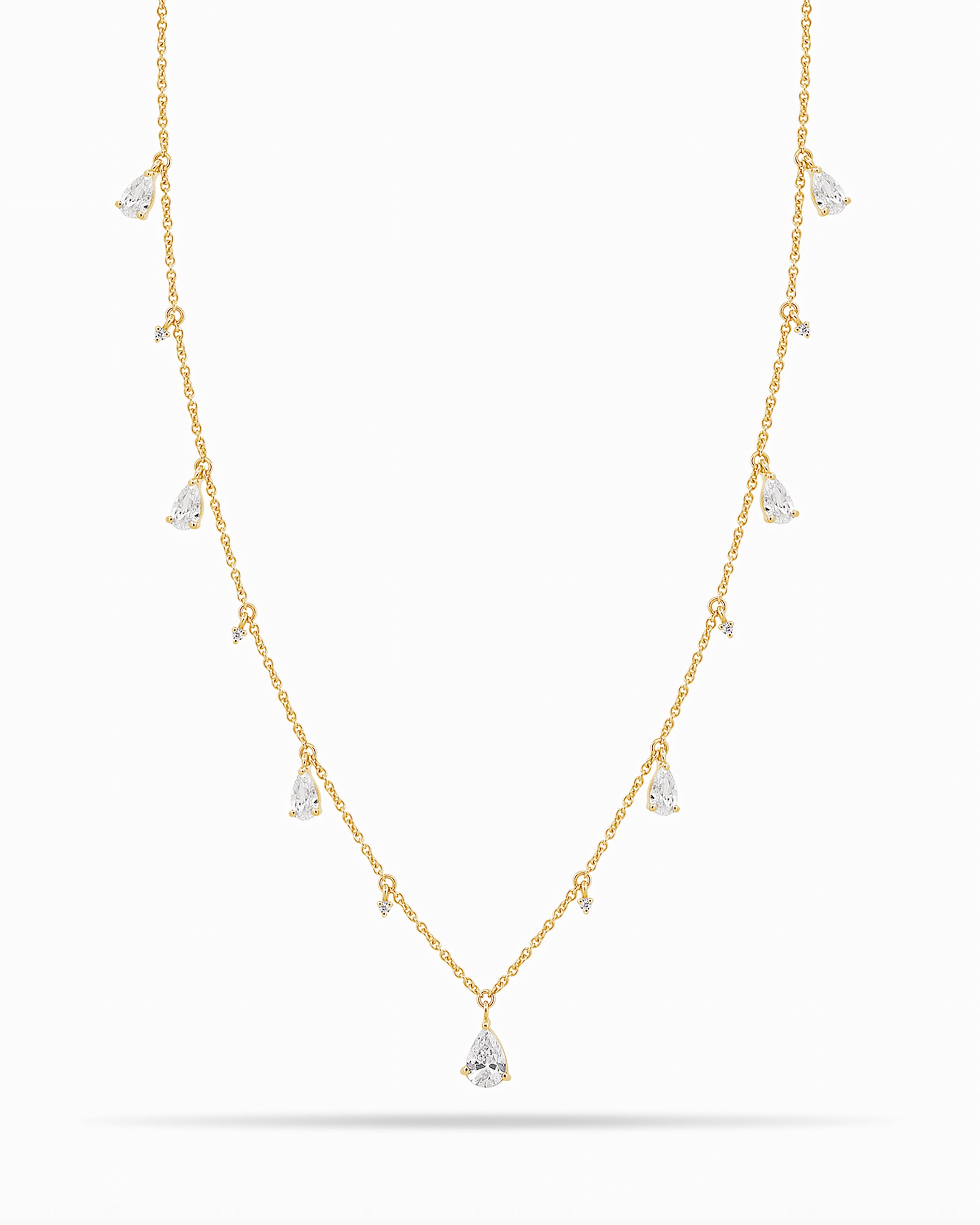 Yellow Gold necklace with teardrop and round diamond pendants on a white background