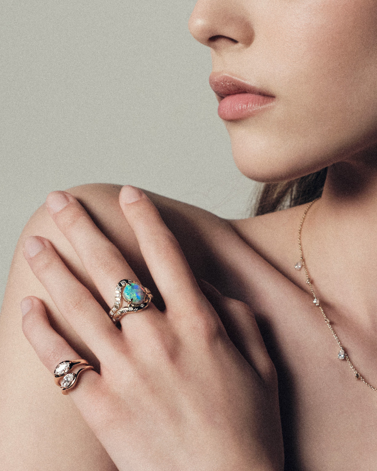 Close-up of a woman's hand wearing an opal ring with a neutral background.