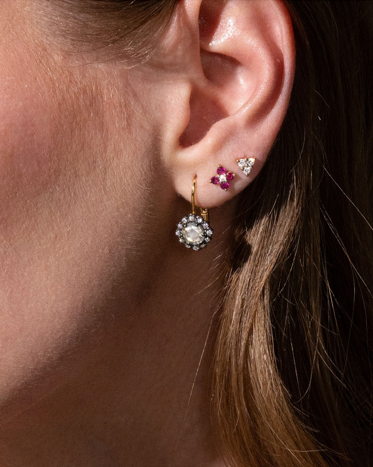 beautiful rose cut diamonds earrings, set in black rhodium 14k or 18k gold, and a dainty trilogy diamonds stud earring on models ear