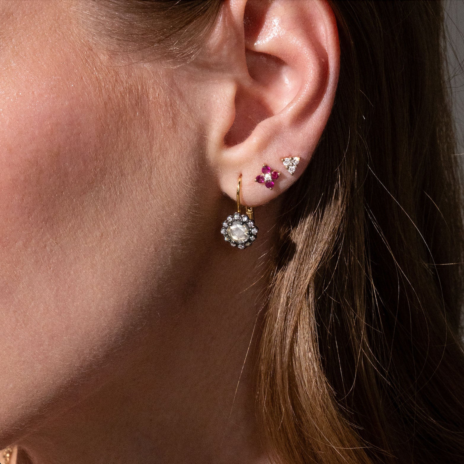 beautiful rose cut diamonds earrings, set in black rhodium 14k or 18k gold, and a dainty trilogy diamonds stud earring on models ear