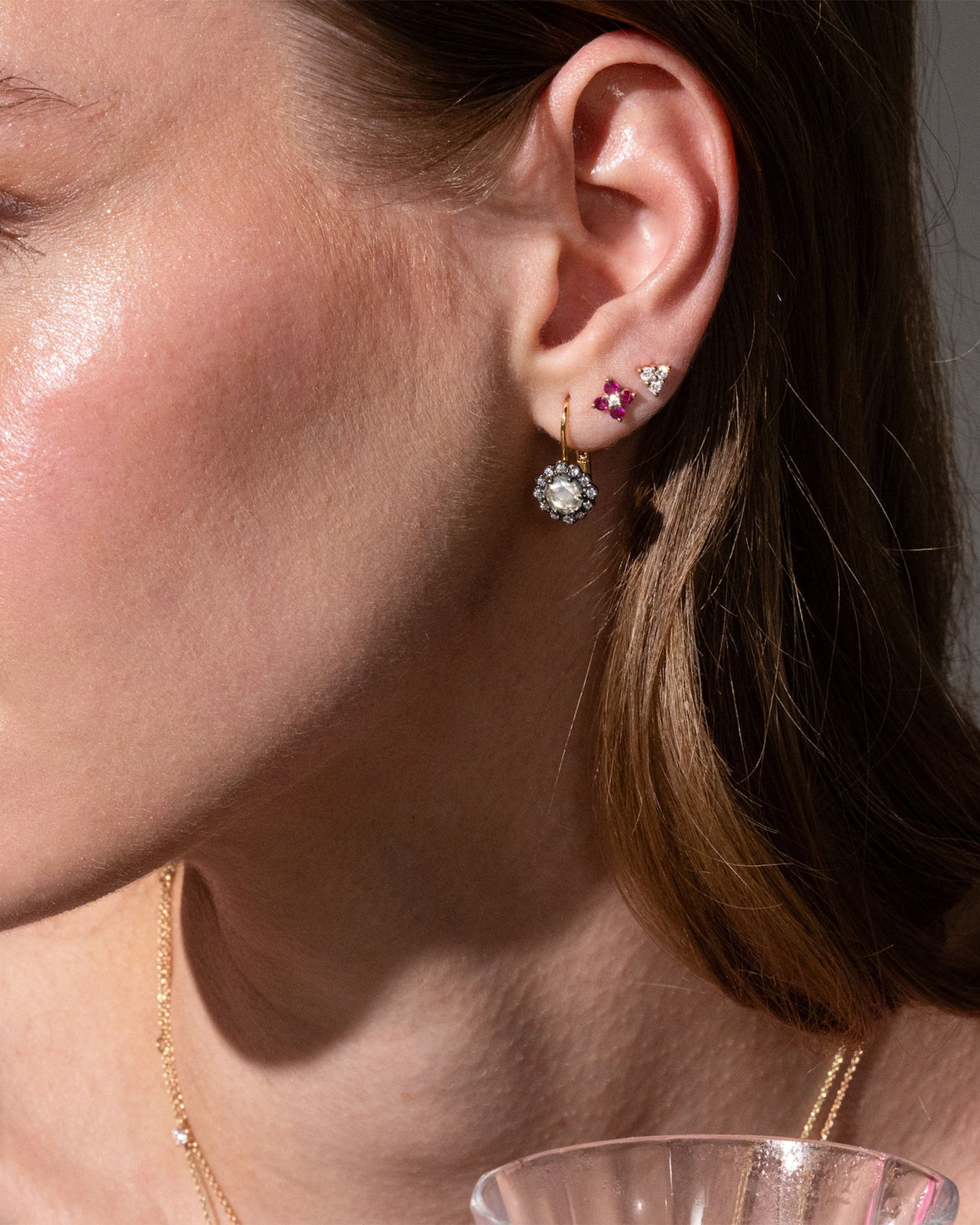 beautiful rose cut diamonds earrings, set in black rhodium 14k or 18k gold, and a dainty trilogy diamonds stud earring on models ear