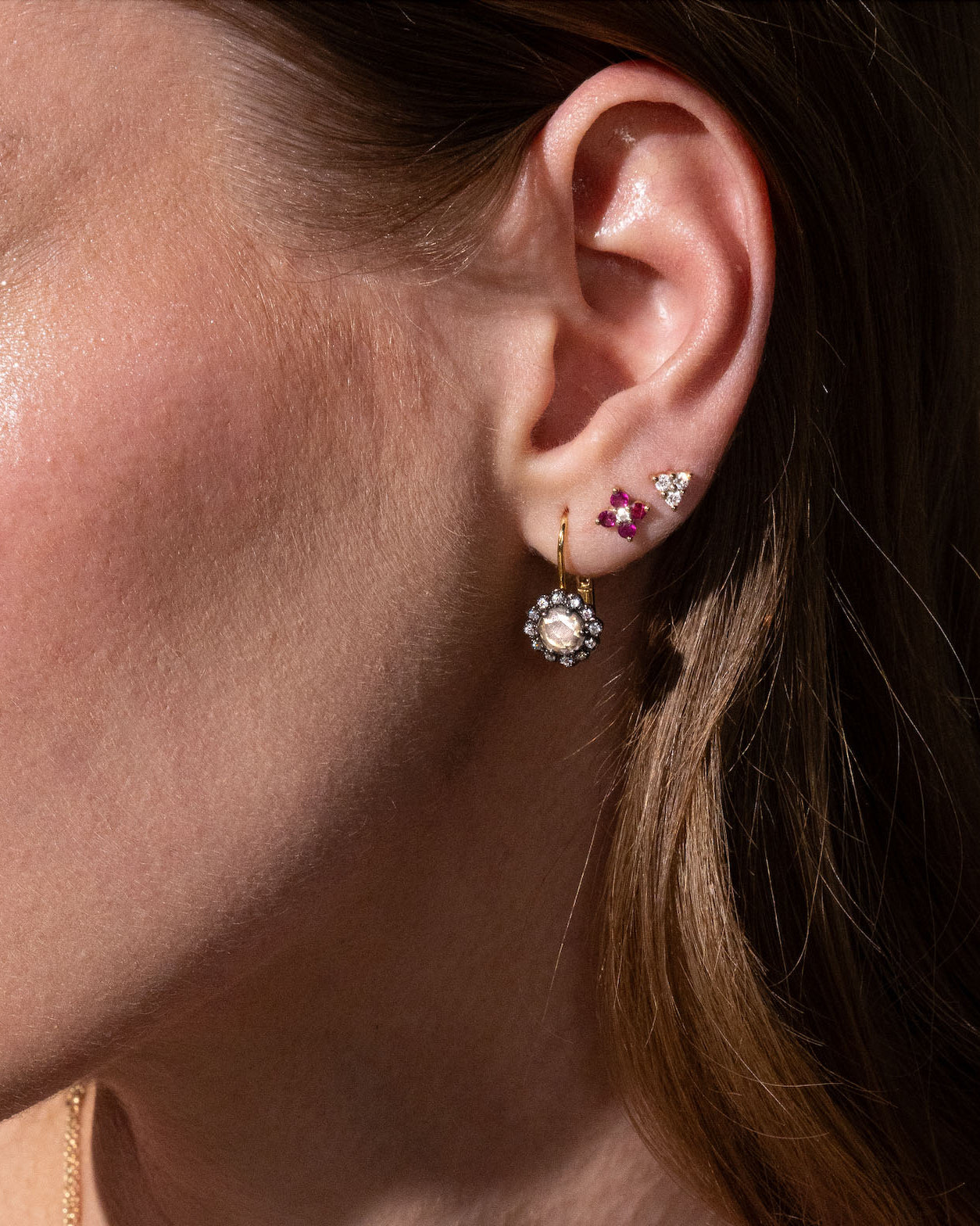 beautiful rose cut diamonds earrings, set in black rhodium 14k or 18k gold, and a dainty trilogy diamonds stud earring on models ear