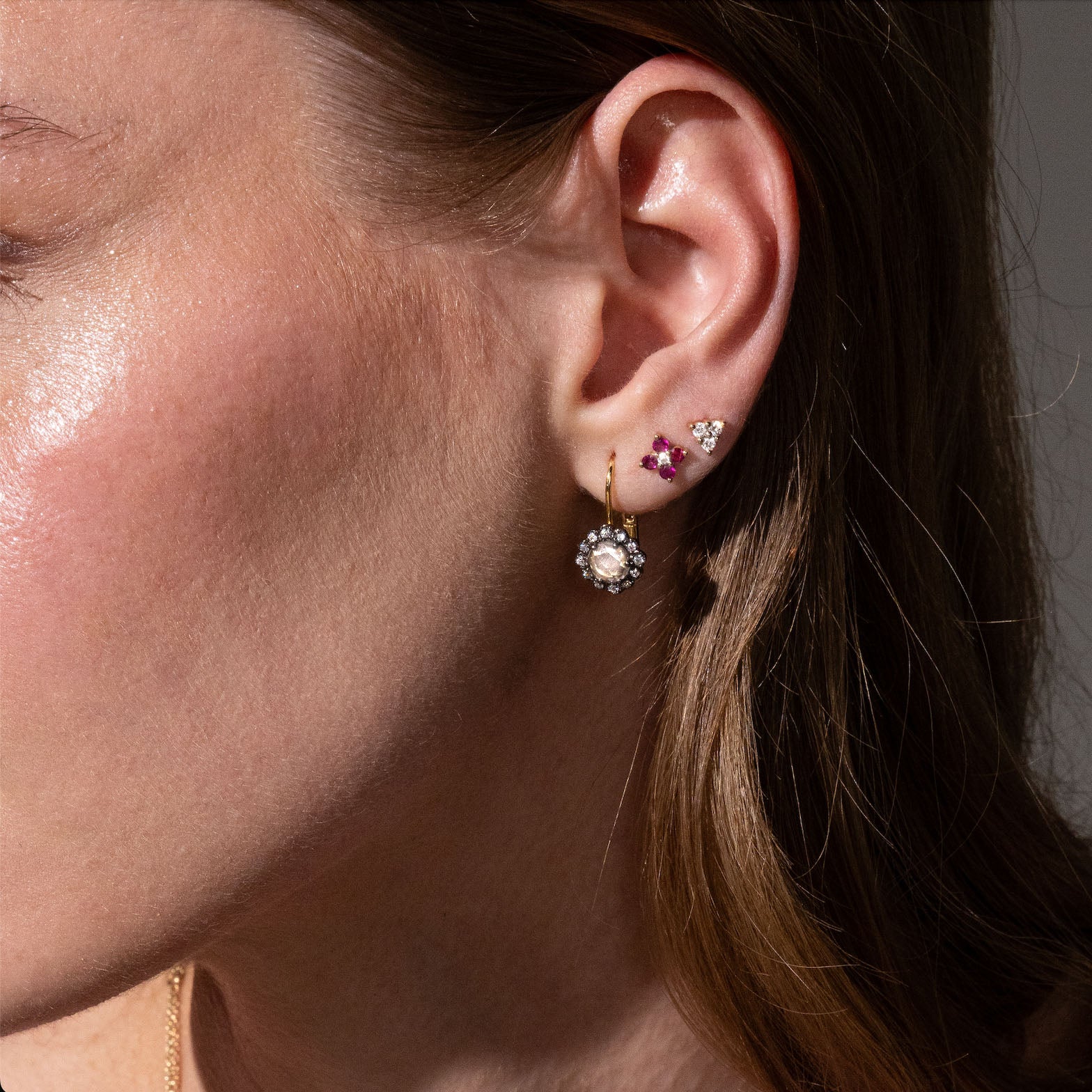 beautiful rose cut diamonds earrings, set in black rhodium 14k or 18k gold, and a dainty trilogy diamonds stud earring on models ear