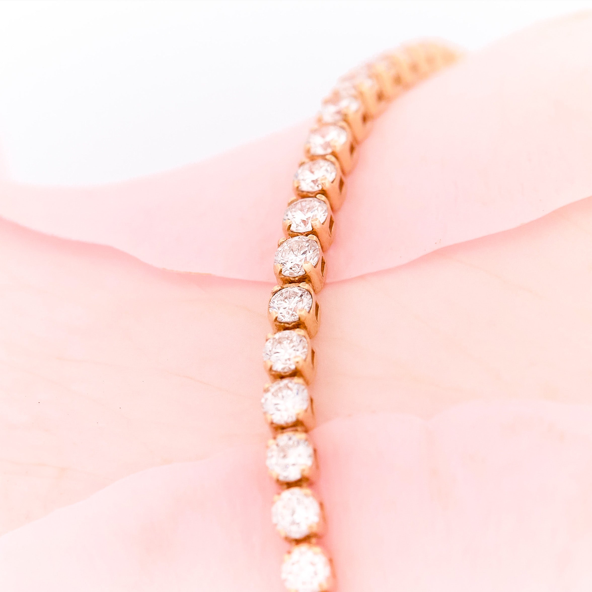 Close-up of a gold bracelet with diamonds on a soft pink fabric background