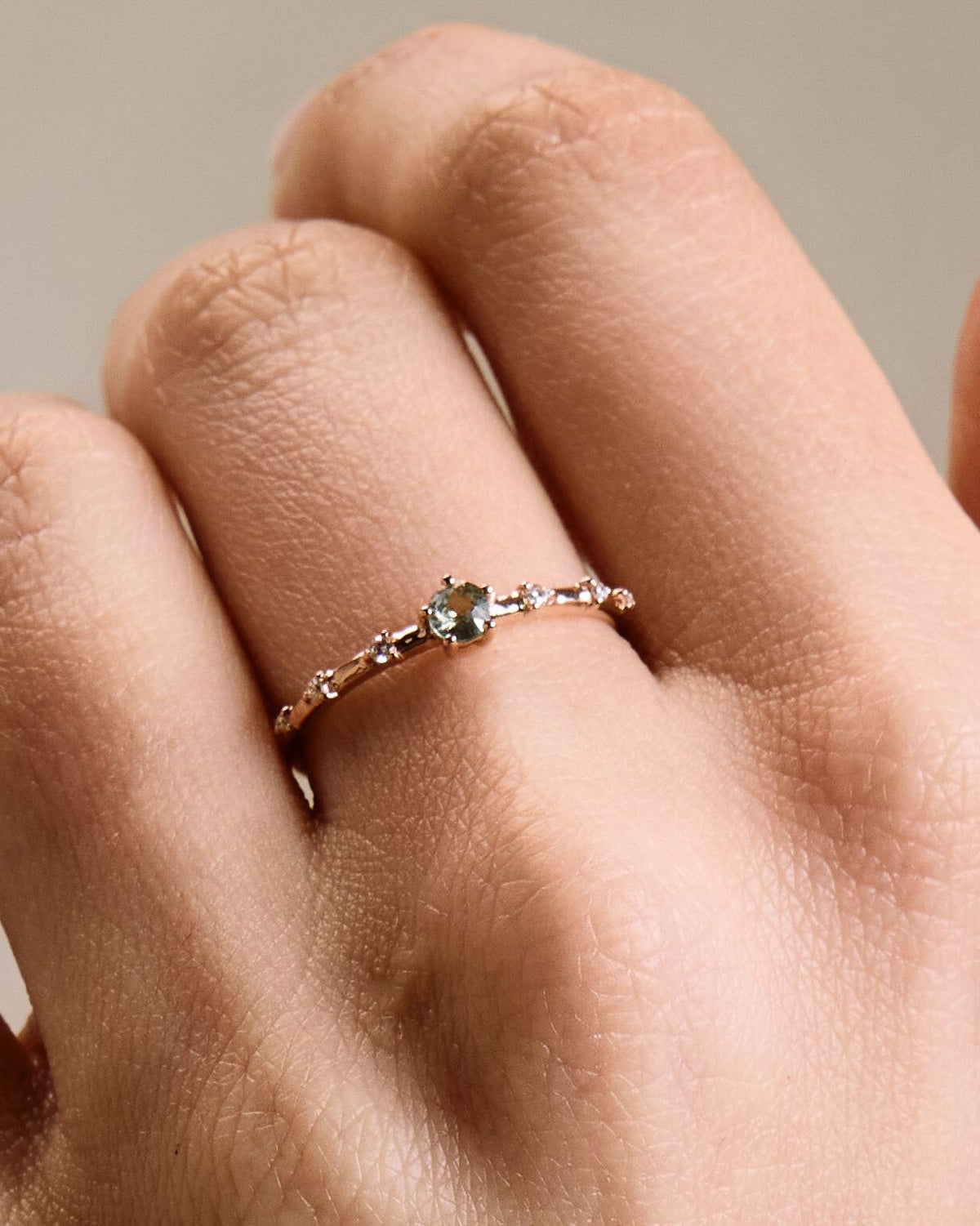 A gold band ring featuring a central sapphire with smaller diamond accents around it, presented on a a hand