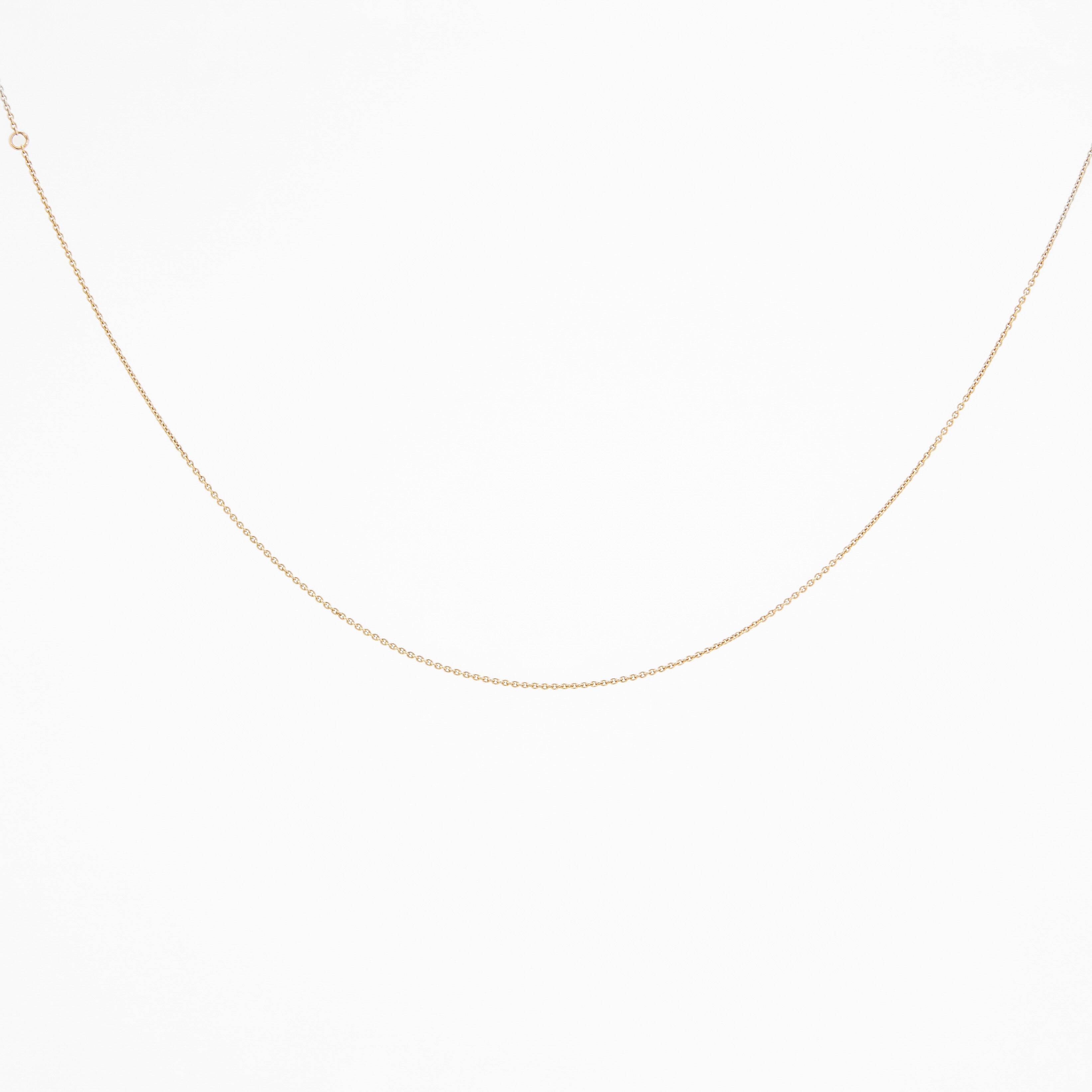 A yellow gold chain necklace laid out on a plain surface.