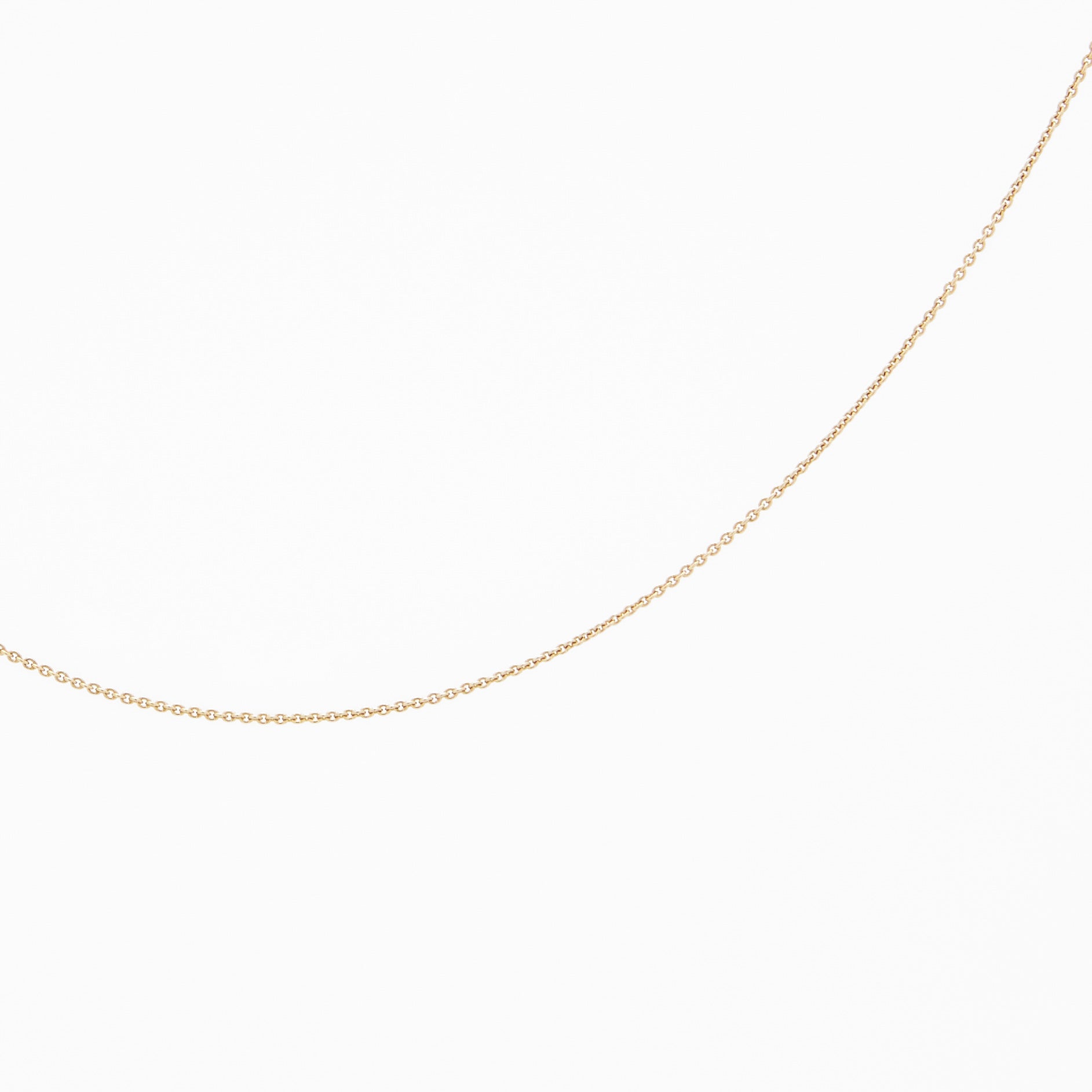 A yellow gold chain necklace laid out on a plain surface.
