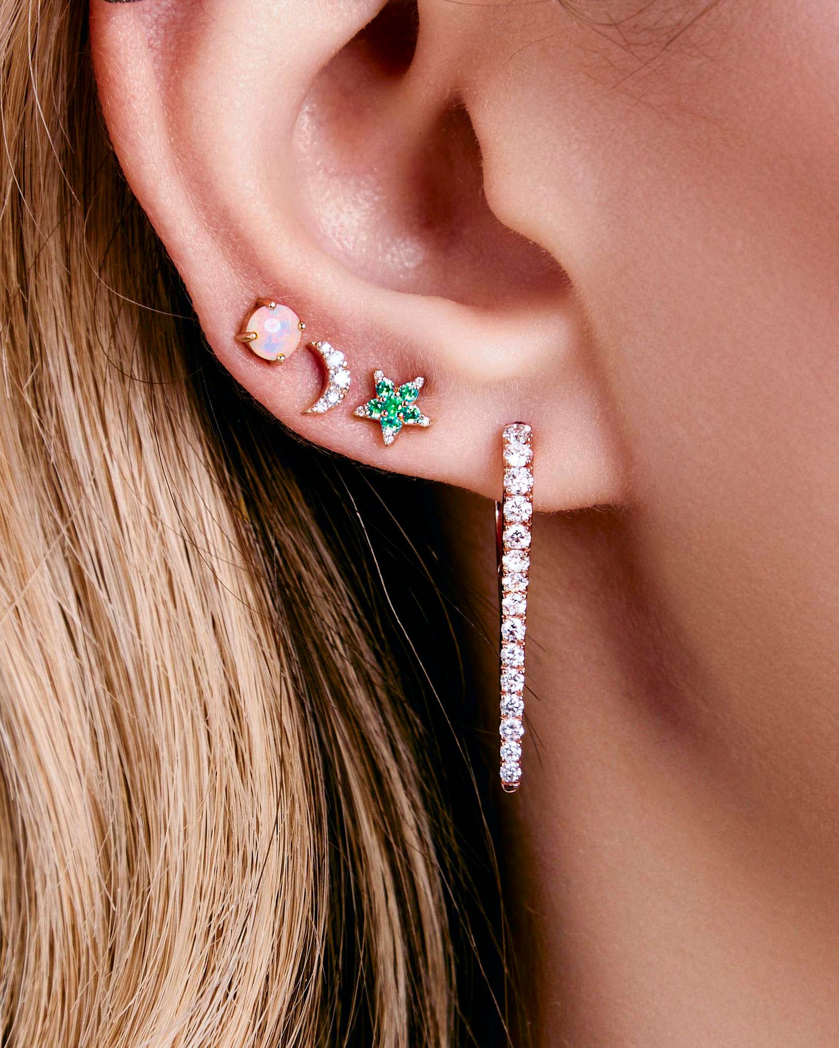 australian opal dot earrings, diamonds moon earrings, emerald and diamonds star earrings, icicle diamonds drop earrings on a model's ear