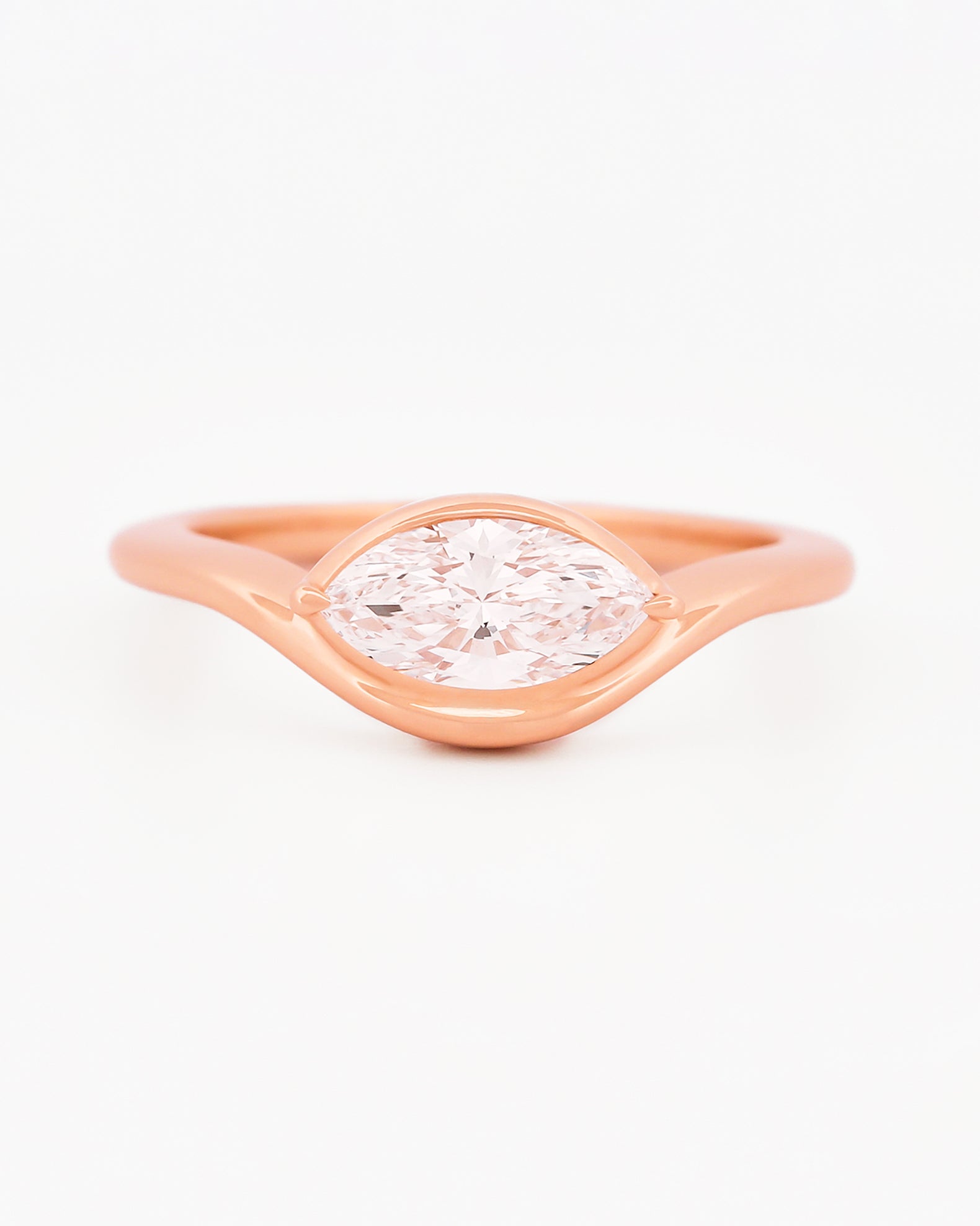 Rose gold solitaire ring with a marquise diamond on a white background.