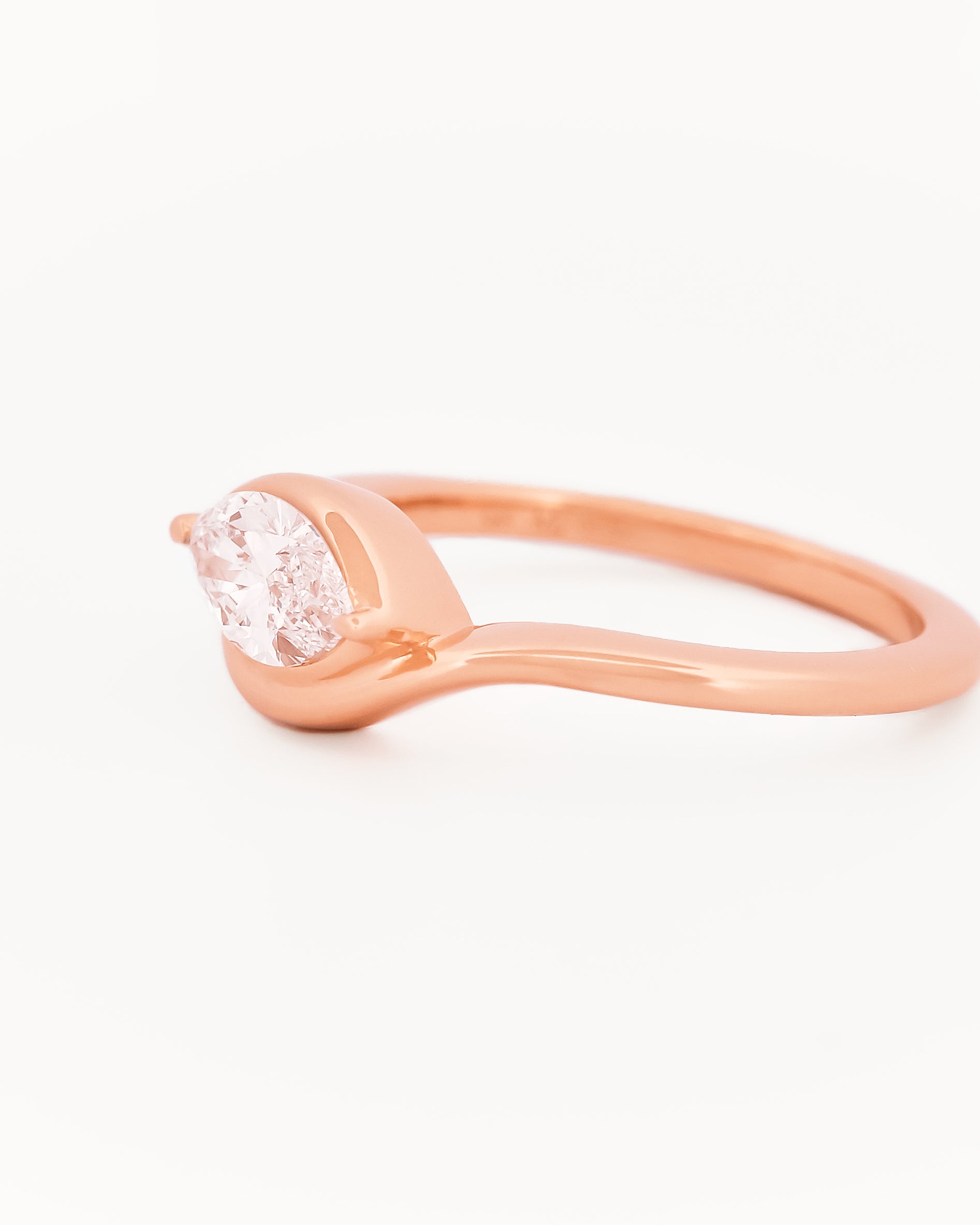Rose gold solitaire ring with a marquise diamond on a white background