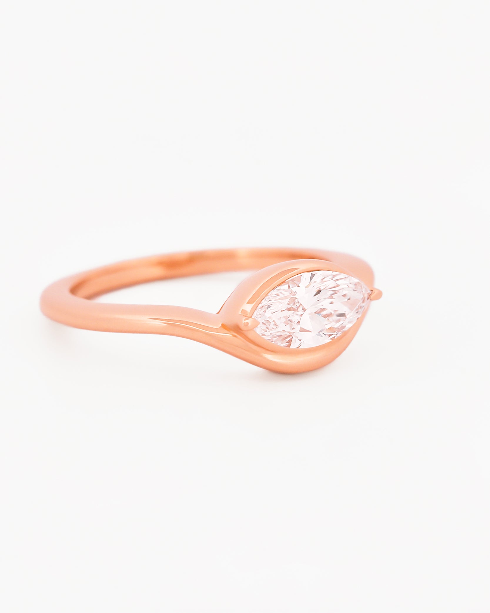 Rose gold solitaire ring with a marquise diamond on a white background