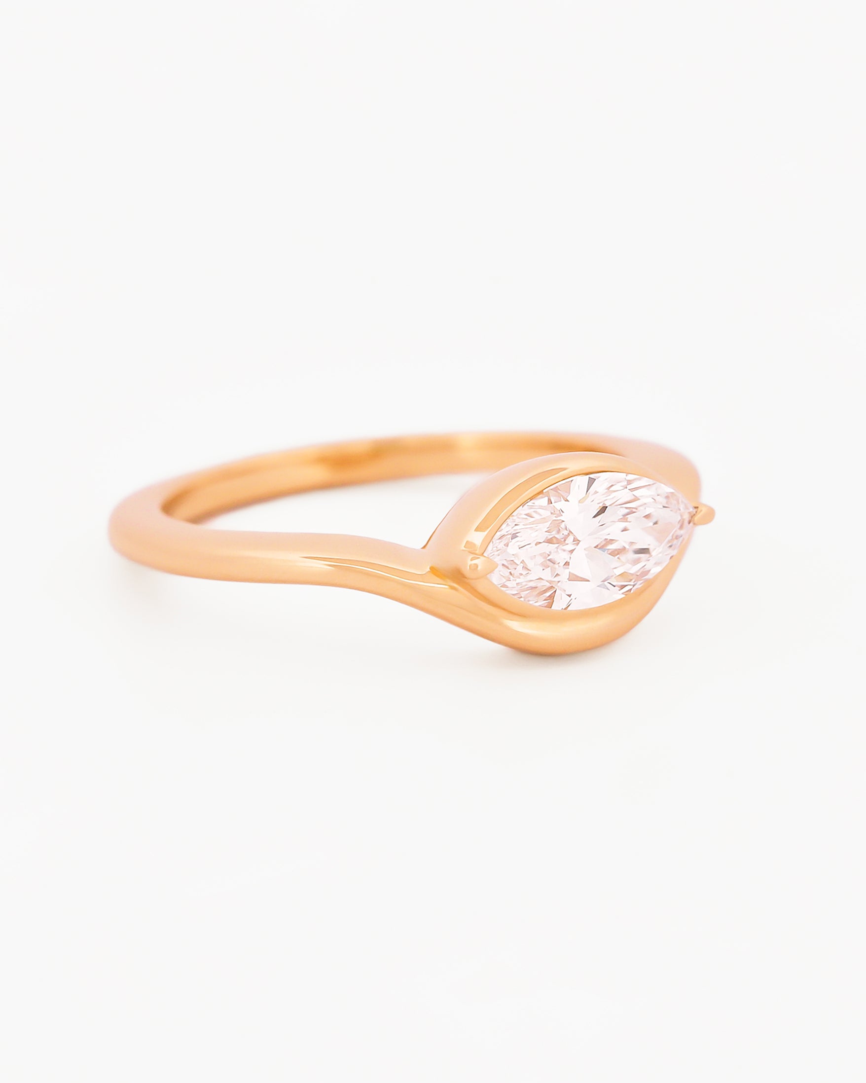 Yellow gold solitaire ring with a marquise diamond on a white background