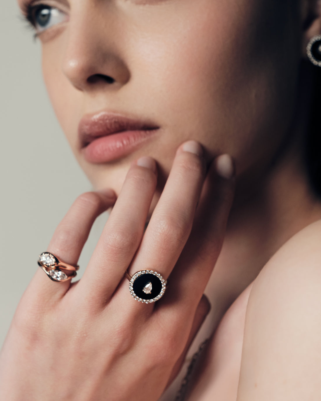A woman wearing a ring with a black onyx and diamonds, two pinky ring with marquise diamonds set in curvy rose gold bands.